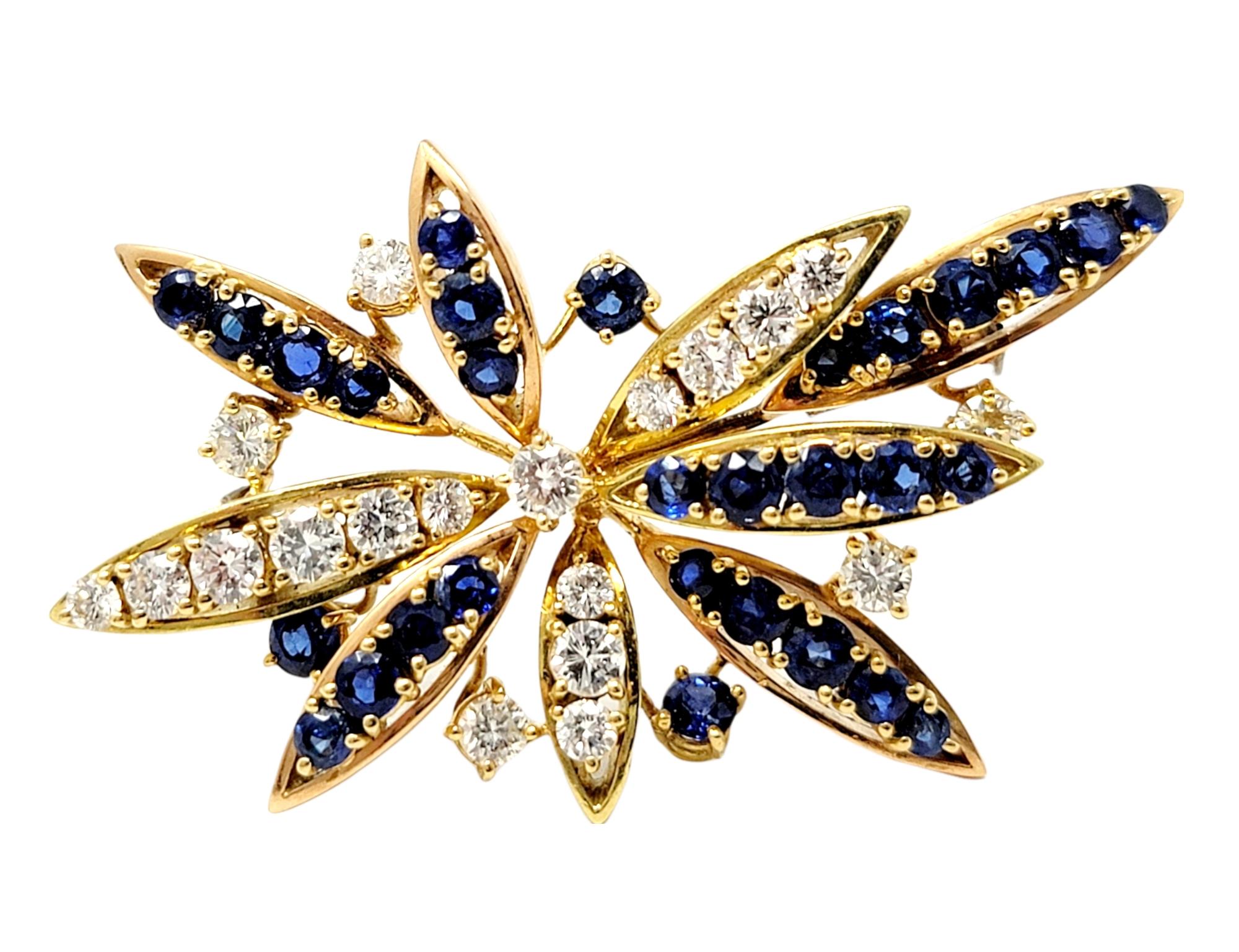 Absolutely exquisite sapphire and diamond floral motif spray brooch. This gorgeous, shimmering piece is bursting with both color and sparkle.  The elegant brooch features multiple layers of elongated, embellished 'petals' prong set with round mixed