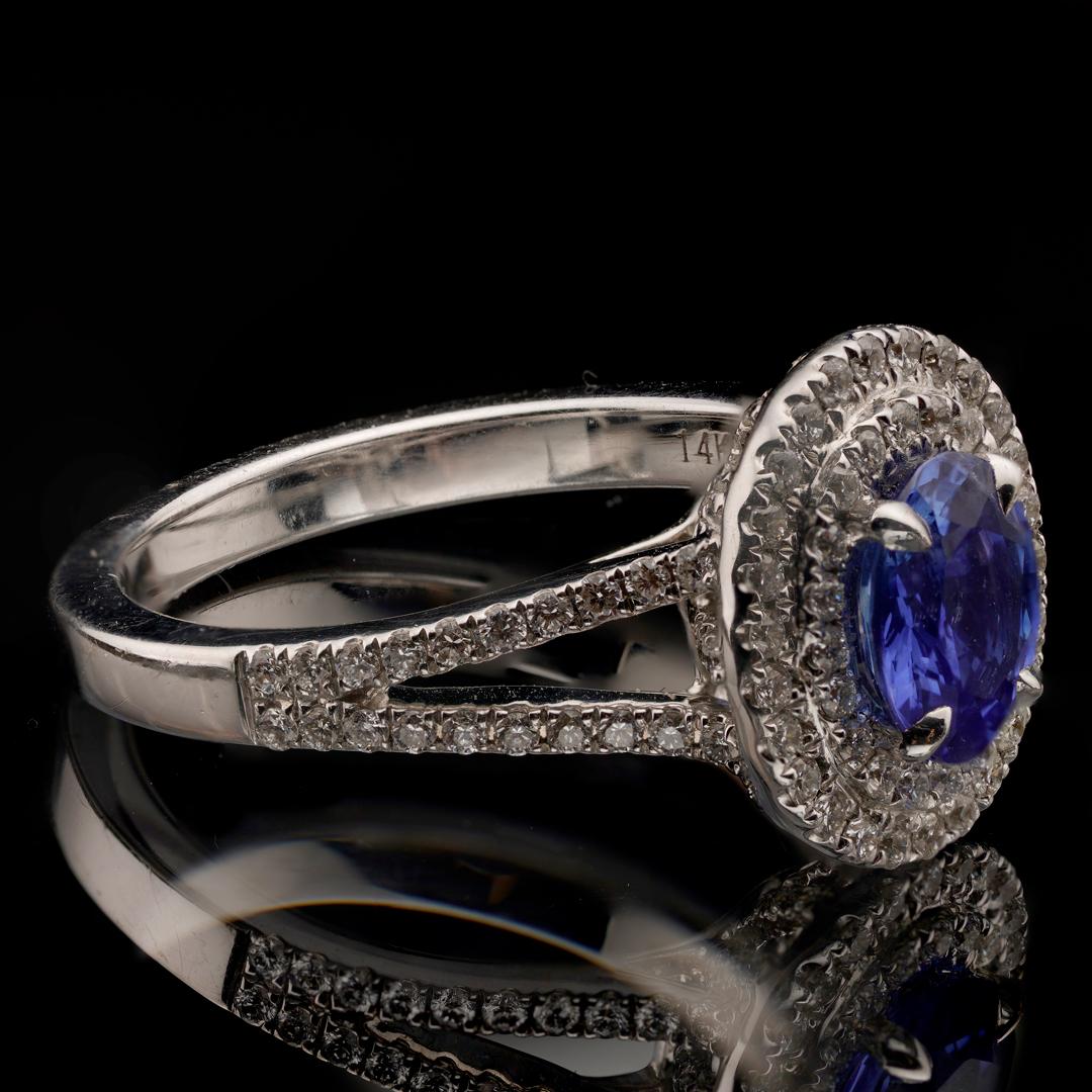 Dieser elegante Ring im Stil eines doppelten Halos besteht aus 124 runden weißen Diamanten, die einen blauen Saphir im Ovalschliff von 1,23 Karat in einem zarten Weißgoldband flankieren. Der exzellent gefärbte Saphir ist GIA-zertifiziert und 100%