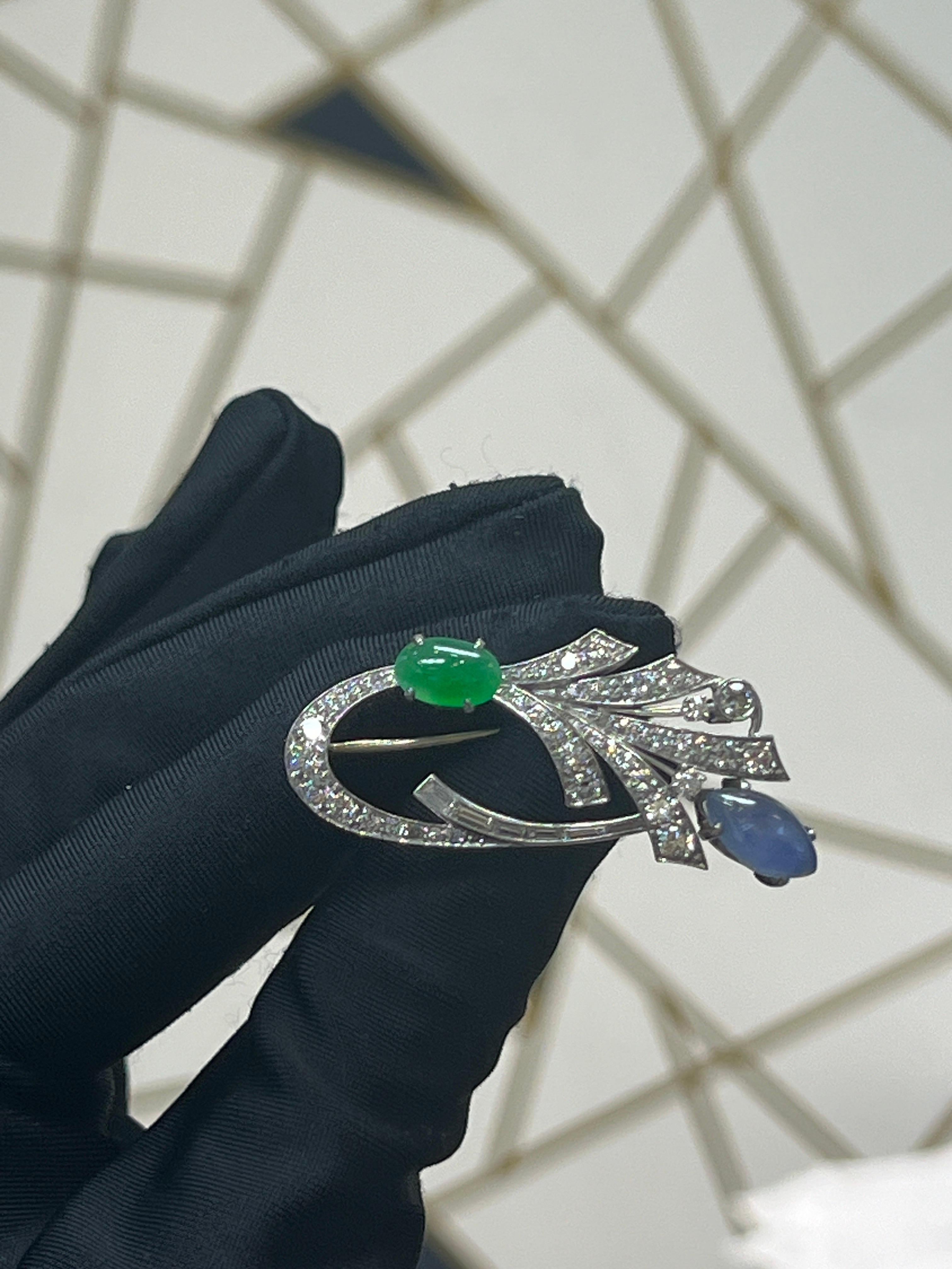 A platinum brooch featuring a cabochon sapphire and a cabochon jade, adorned with six baguette diamonds and forty-five round-cut diamonds

Approximate Length: 2