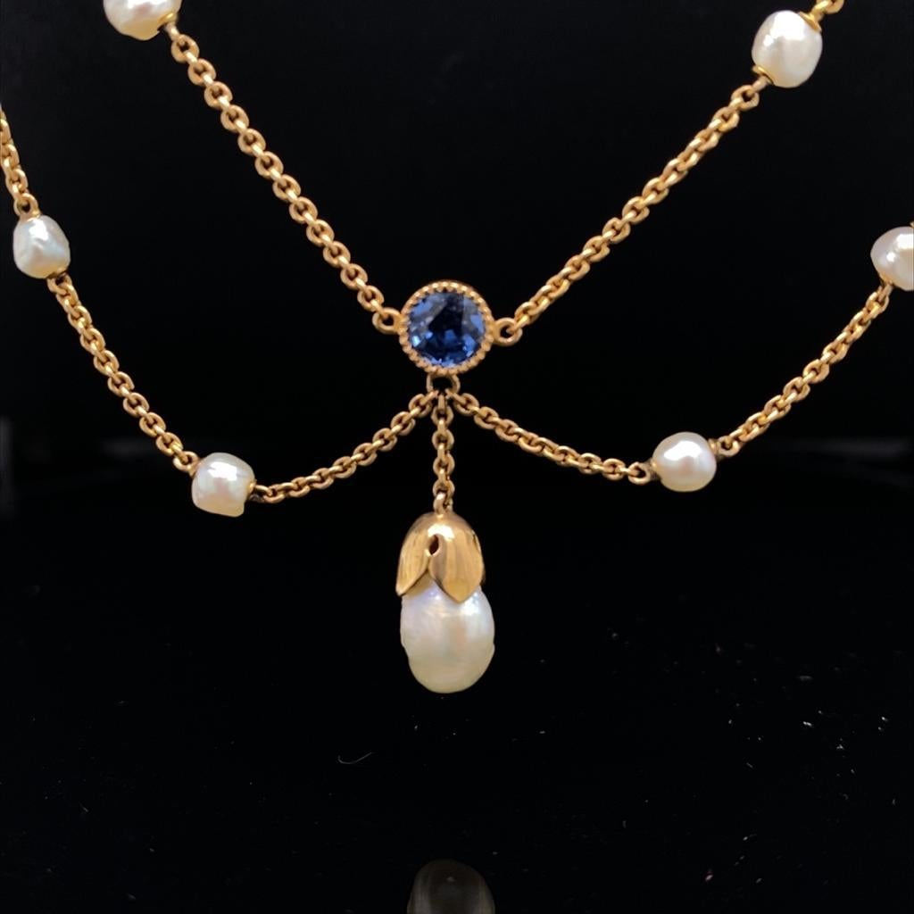 A sapphire and pearl necklace 14 karat white gold, circa 1900.

This sweet and elegant necklace comprises of four beautifully sweeping scrolls festooned with royal blue round cut sapphires and freshwater pearls, set to its centre with an impressive