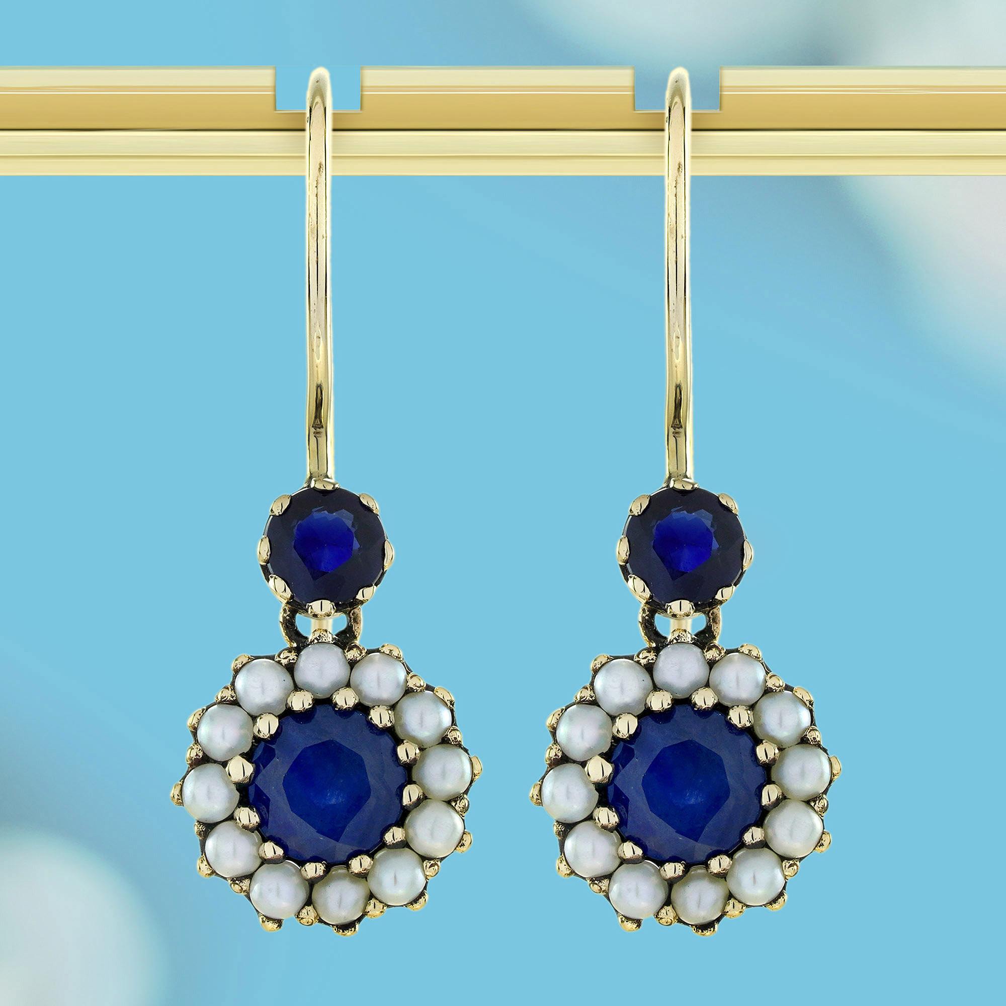 Diese floralen Hakenohrringe im Vintage-Stil haben einen runden Saphir in der Mitte, der Eleganz symbolisiert. Das von schimmernden Perlen umgebene Design ahmt die zarten Blütenblätter einer Blume nach. Ein kleiner runder Saphir sitzt oben auf dem