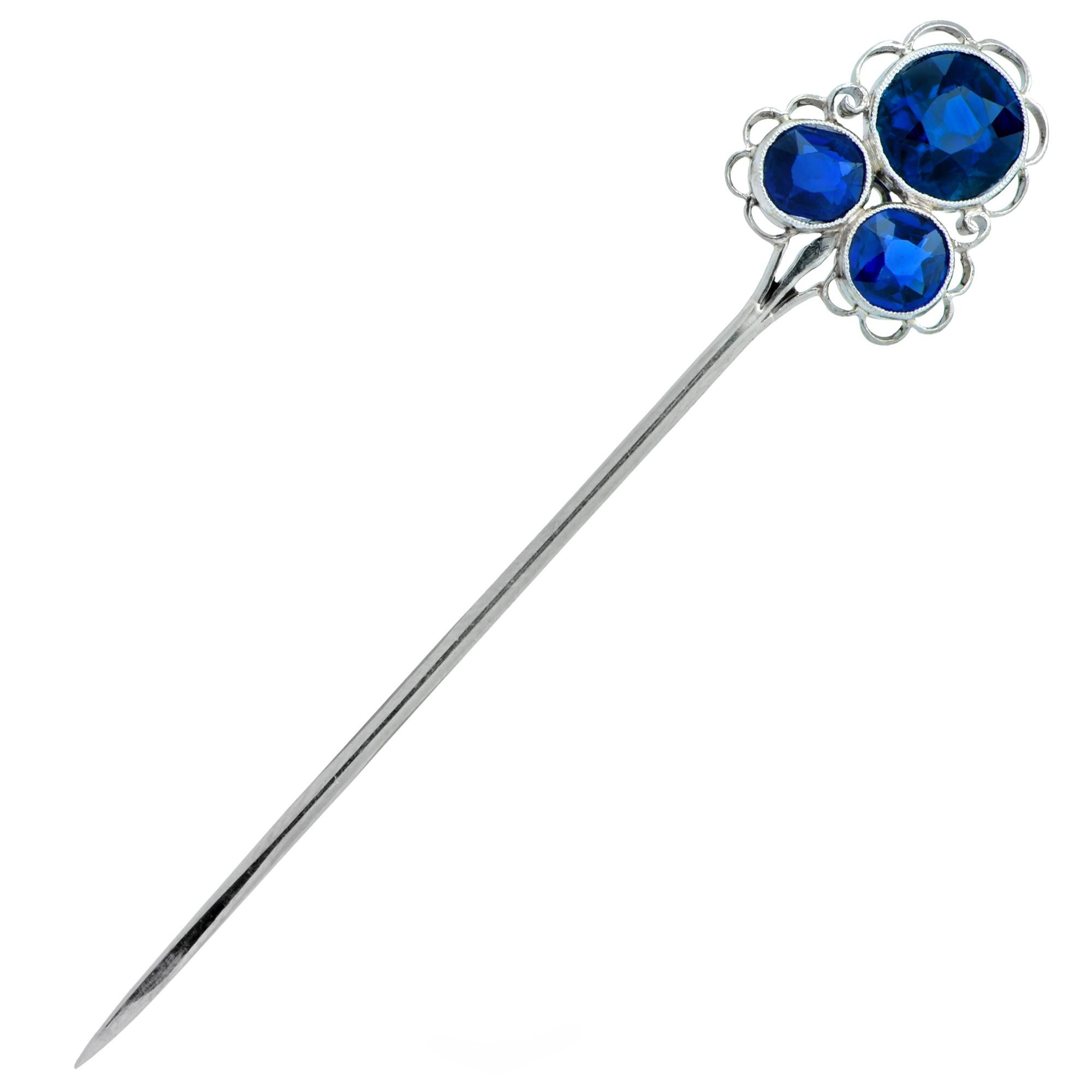 Delightful  brooch pin crafted in platinum, featuring 2.50 carats total weight of round blue sapphires. 1 round cut sapphire weighing approximately 1.50 carats, rests on 2 round cut sapphires weighing approximately 1 carat total, adorned with fine