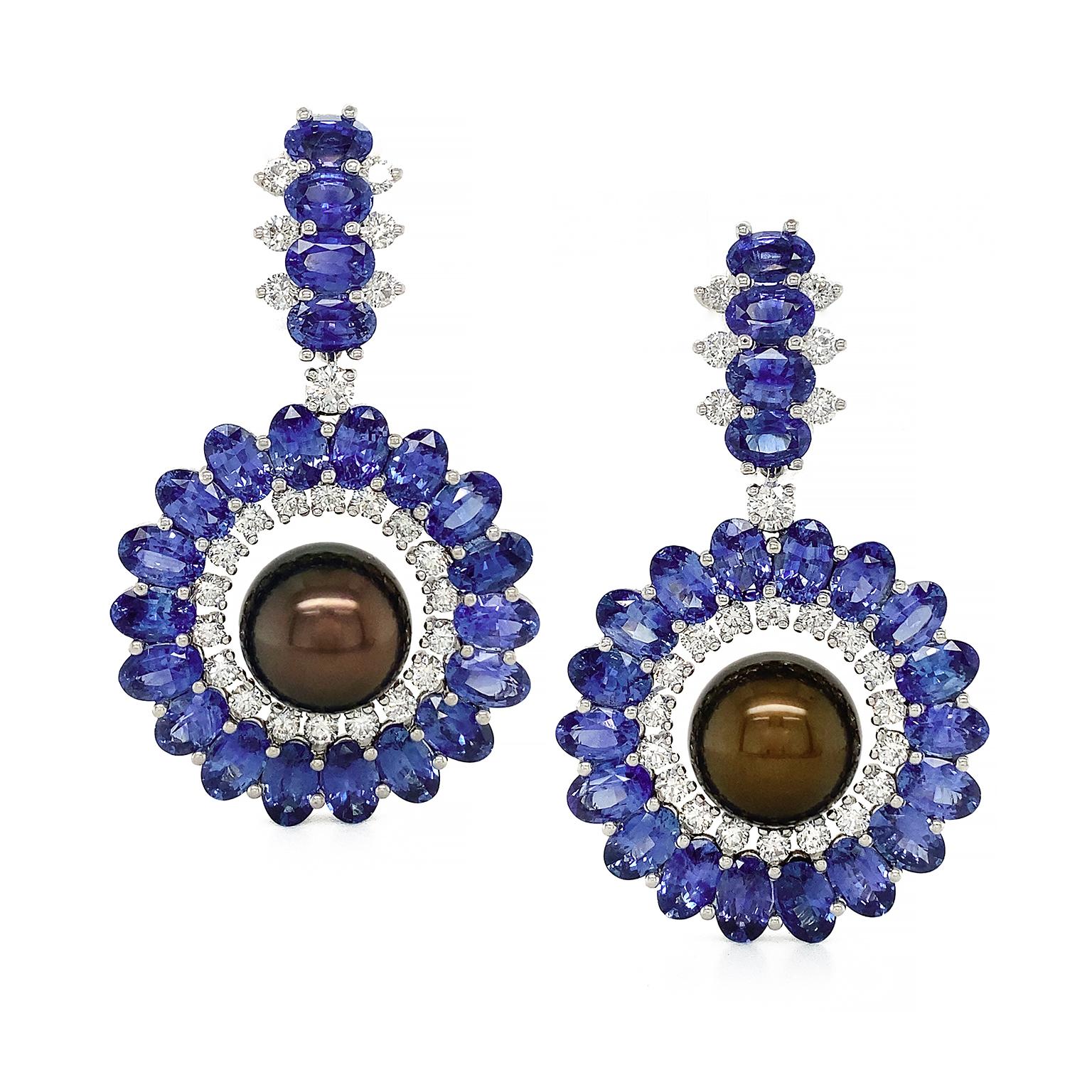 Vibrant indigo and navy shades of sapphires sparkle in these earrings. The design begins with a single row of four oval sapphires, which feature brilliant cut diamonds on the sides. A single diamond leads to a climax of sapphires arranged in a