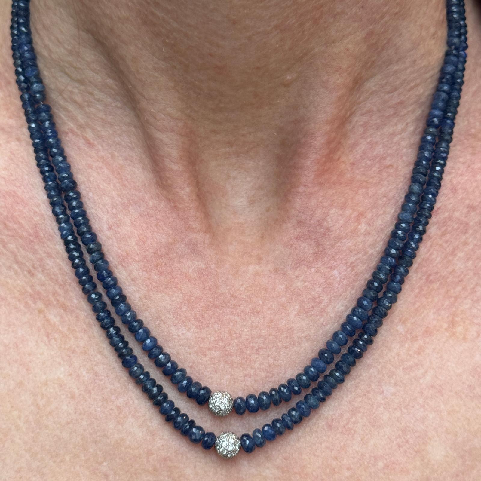 Questa elegante collana a due file in oro bianco 14 carati è caratterizzata da vibranti perle di zaffiro blu, splendidamente accentuate da due stazioni a sfera di diamanti e da una chiusura con diamanti. I diamanti, per un totale di circa 0,50