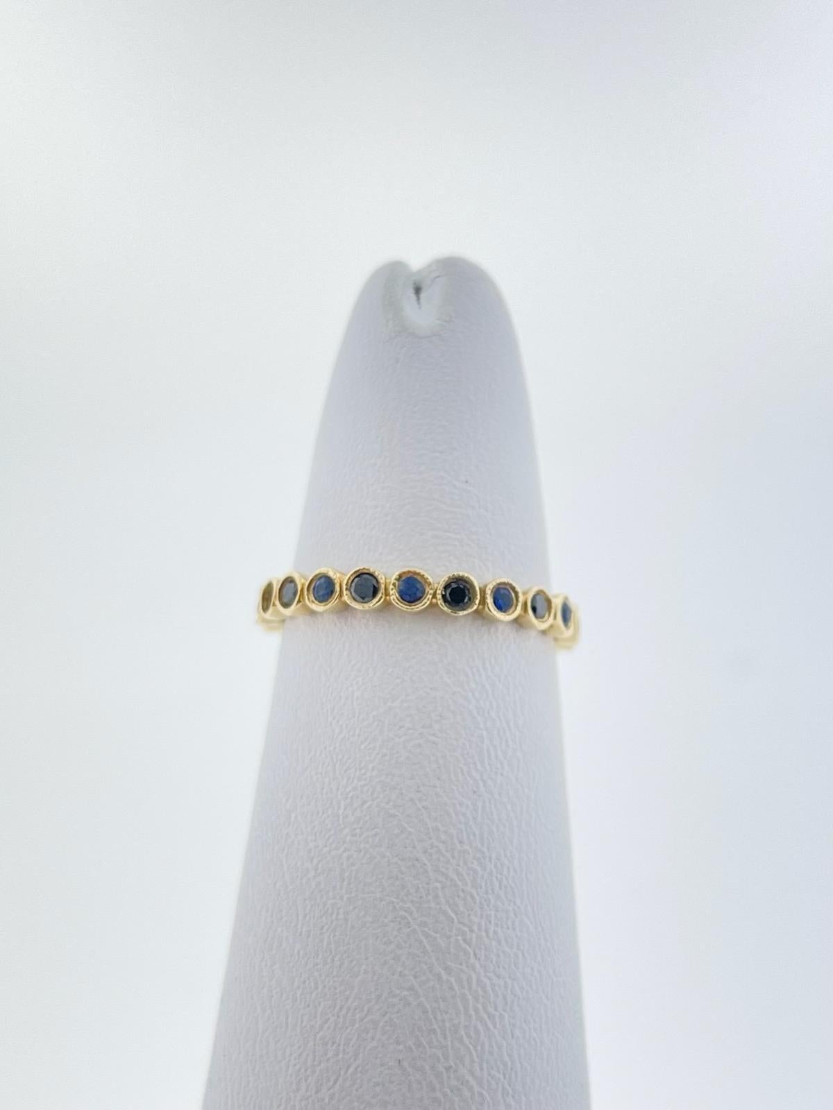 This eternity band is set in 14K Yellow Gold with alternating blue sapphire and black diamond stones. There is a total of Ten (10) Round Blue Sapphires weighing 0.17ctw and Eleven (11) Round Black Diamonds weighing 0.15ctw. 

The ring is currently