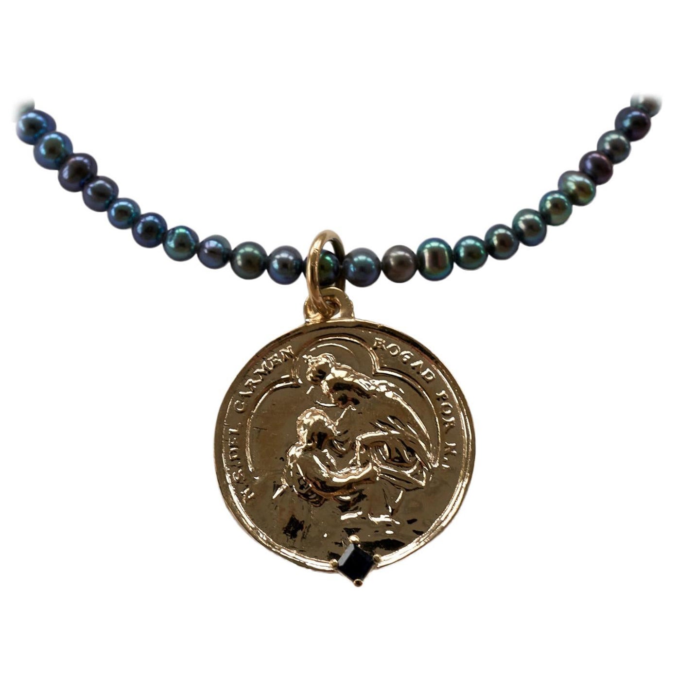 Sapphire Virgin del Carmen Medal Necklace Coin Pendant Chain Black Pearl J Dauphin

This necklace features a medal of the Virgin Del Carmen adorned with a square-cut blue sapphire, suspended from a striking black pearl bead necklace. The blue