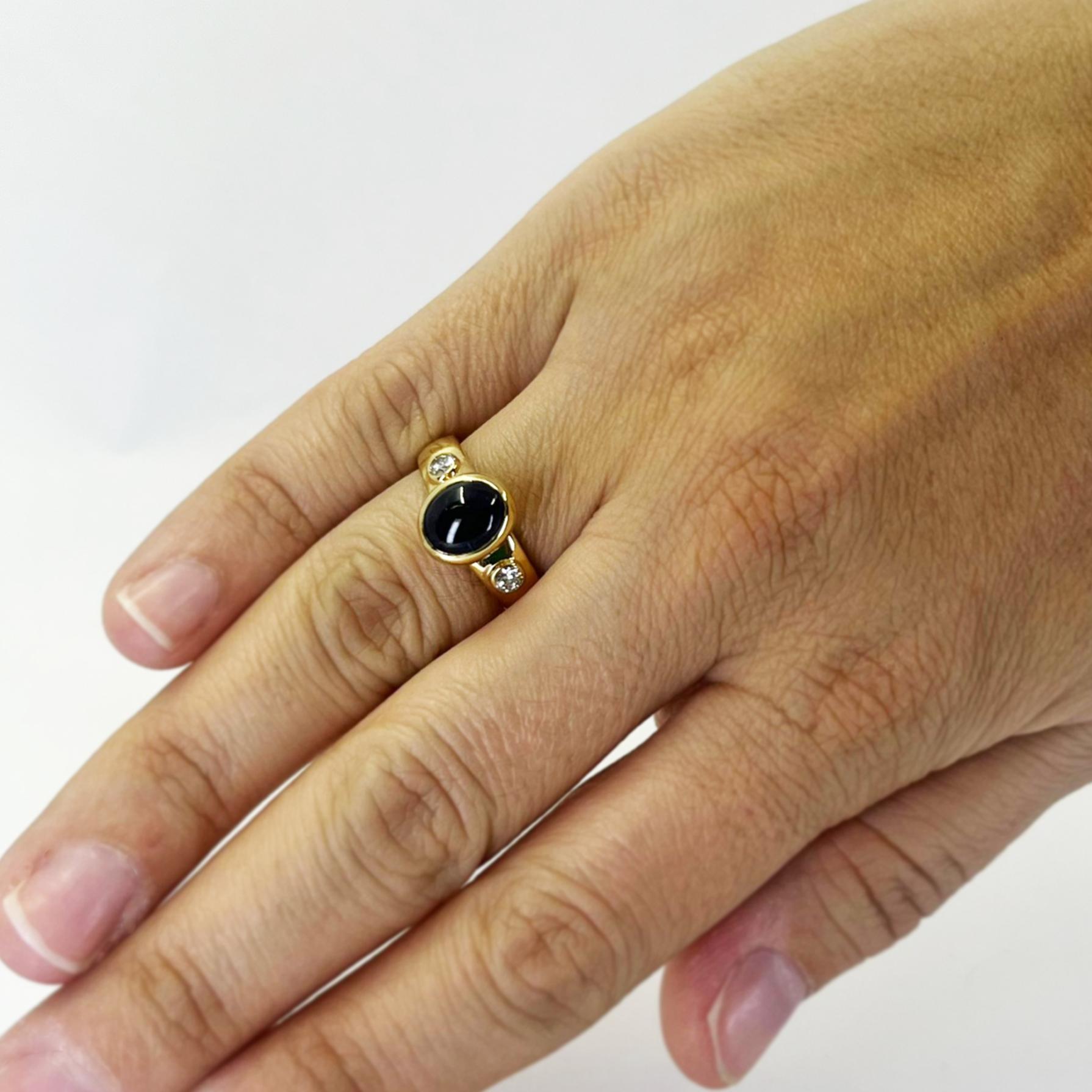 18 karat yellow gold ring featuring an oval cabochon sapphire estimated to weight 1.00 carat accented by 2 round diamonds of VS clarity and H color totaling approximately 0.20 carats. Finger size 6.5. Includes One Sizing Service Prior to Shipping,