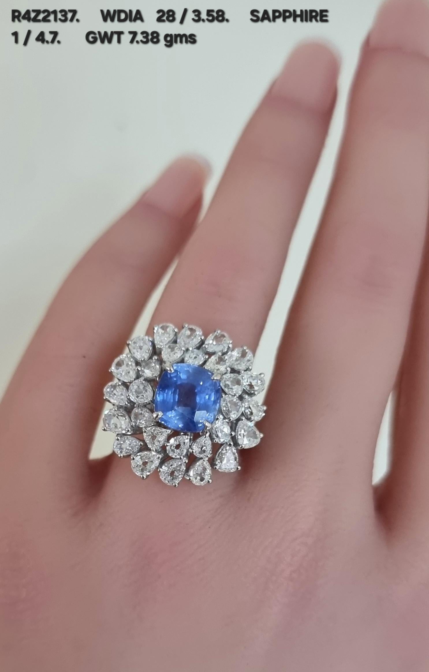 A masterpiece of timeless elegance, this exquisite ring features a captivating cushion-shaped blue sapphire weighing 4.70cts., at its center, radiating deep, velvety hues. Surrounding the majestic gemstone, halo of luminous pear-shaped diamonds