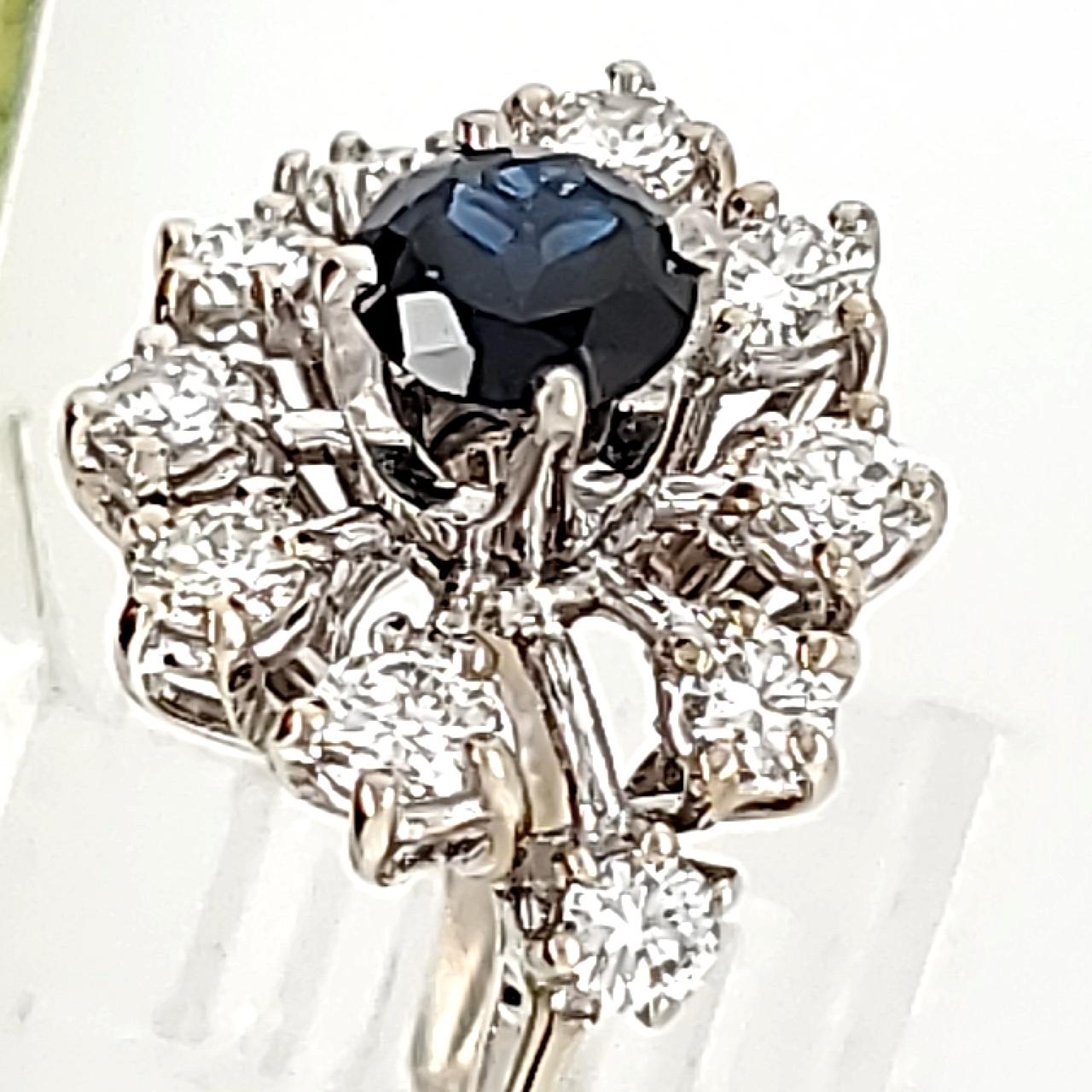 An estate piece originally purchased about 30 years ago at the Famous Brimfield Antique Show.  Center stone was removed and replaced with a 71pt round dark blue sapphire - reminiscent of those to be found in older jewelry.  Diamonds are fairly