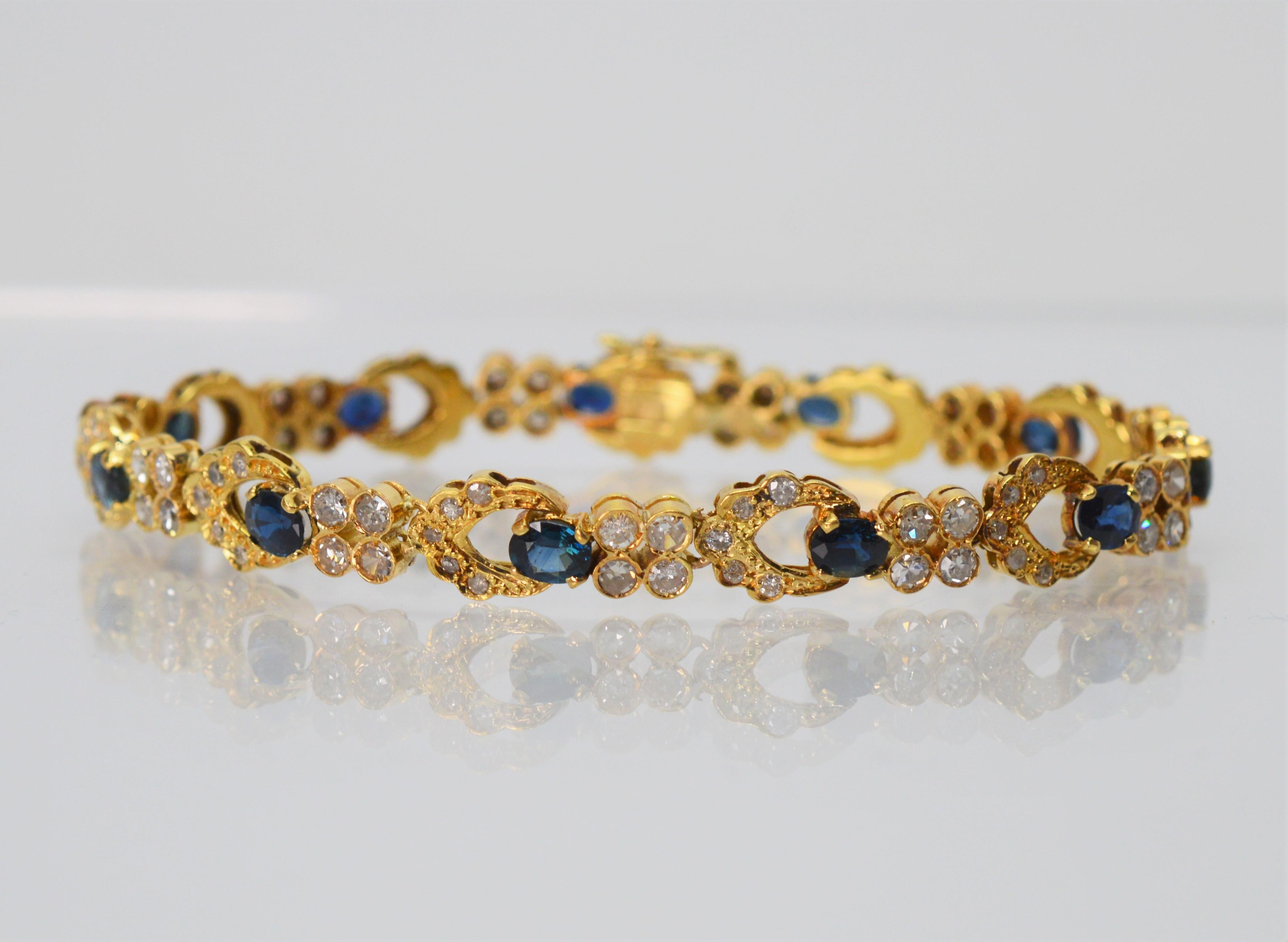 A truly romantic bracelet, beautifully feminine with its classic display of diamond and sapphire floret links.  Set in eighteen karat (18K) yellow gold, this estate piece glistens with over 100 diamonds for a 2.75 carat diamond total weight and