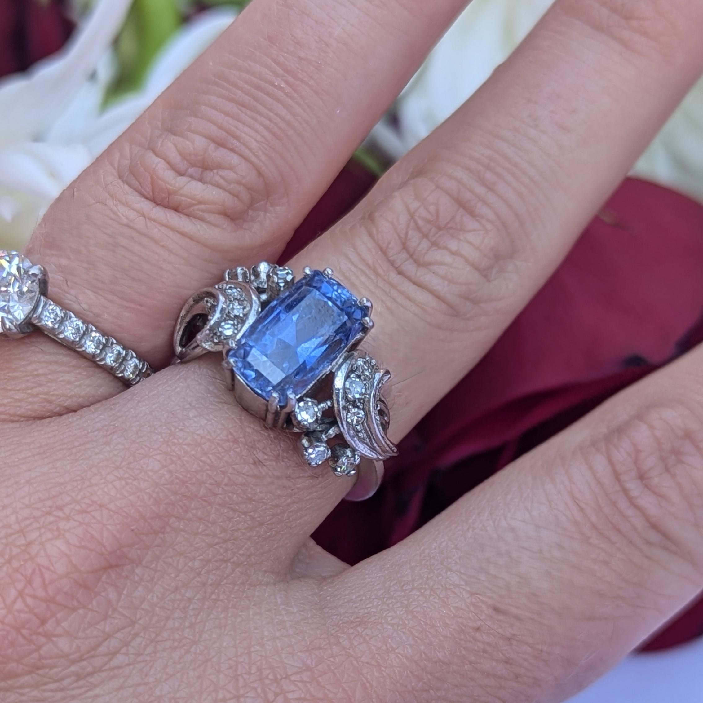 Cette bague en or blanc 18 carats présente un saphir de taille coussin pesant environ 5,40 carats, entouré d'une grappe de diamants de taille unique.
