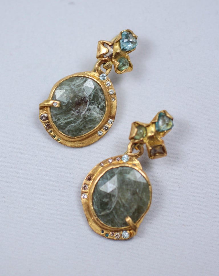 Lagoon dangle drop earrings. Brown diamonds, zircons, demantoid garnets are set in 21k gold creative bezels, 18k gold ear wires. Hanging large blue-green sapphires are set in bezels and are surrounded by brown, blue, and white diamonds.