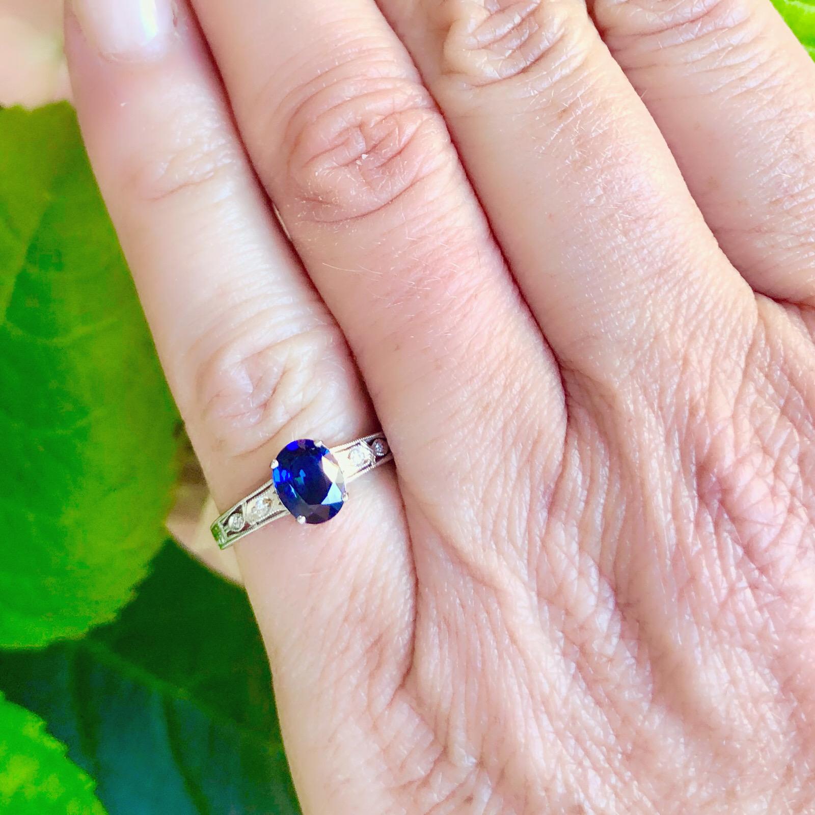 This classic design 18k white gold ring features an oval-cut blue sapphire weighing 1.12 carats, with 4 round brilliant-cut diamond accents adding sparkle and shine. The ring weighs 2.4 grams, and is currently size 5 3/4, with easy up or down