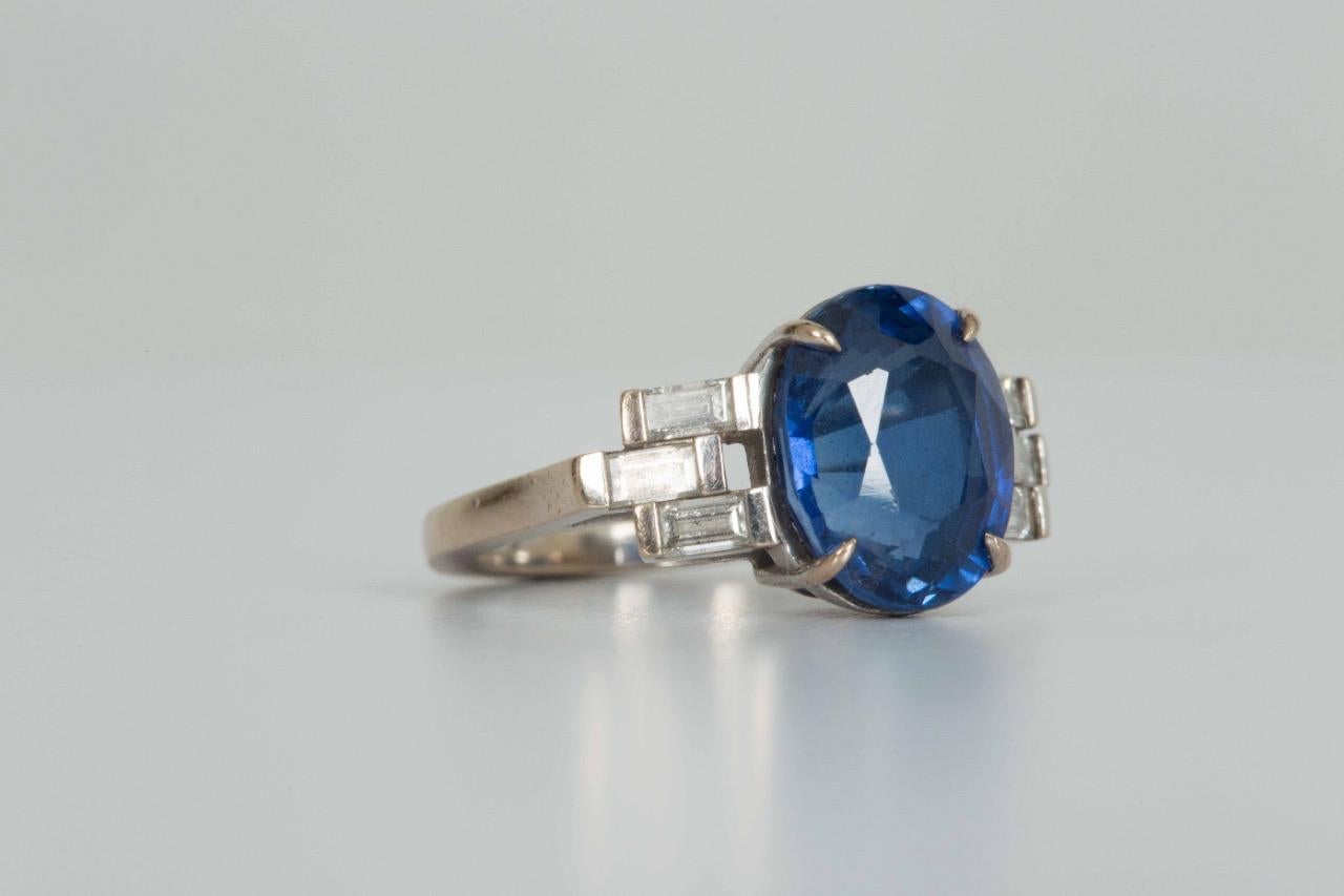Sapphire and Diamond Art Deco Style cocktail ring. Oval shaped saphire set in 18 carat white gold with three diamond baguettes on each side. 
