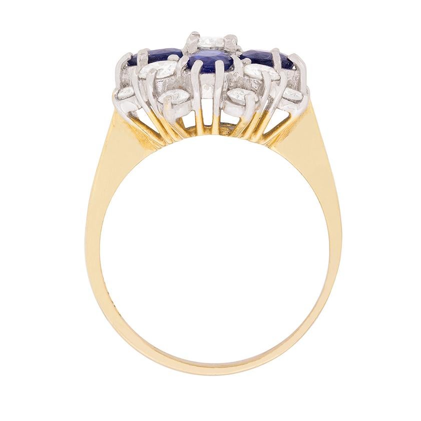 This fabulous circa 1973 cocktail ring flashes with one carat of round brilliant cut diamonds mingling amongst one carat oval-shaped sapphires set at each of its four cardinal points, all hand-set in 18 carat white gold. The balance of the ring is
