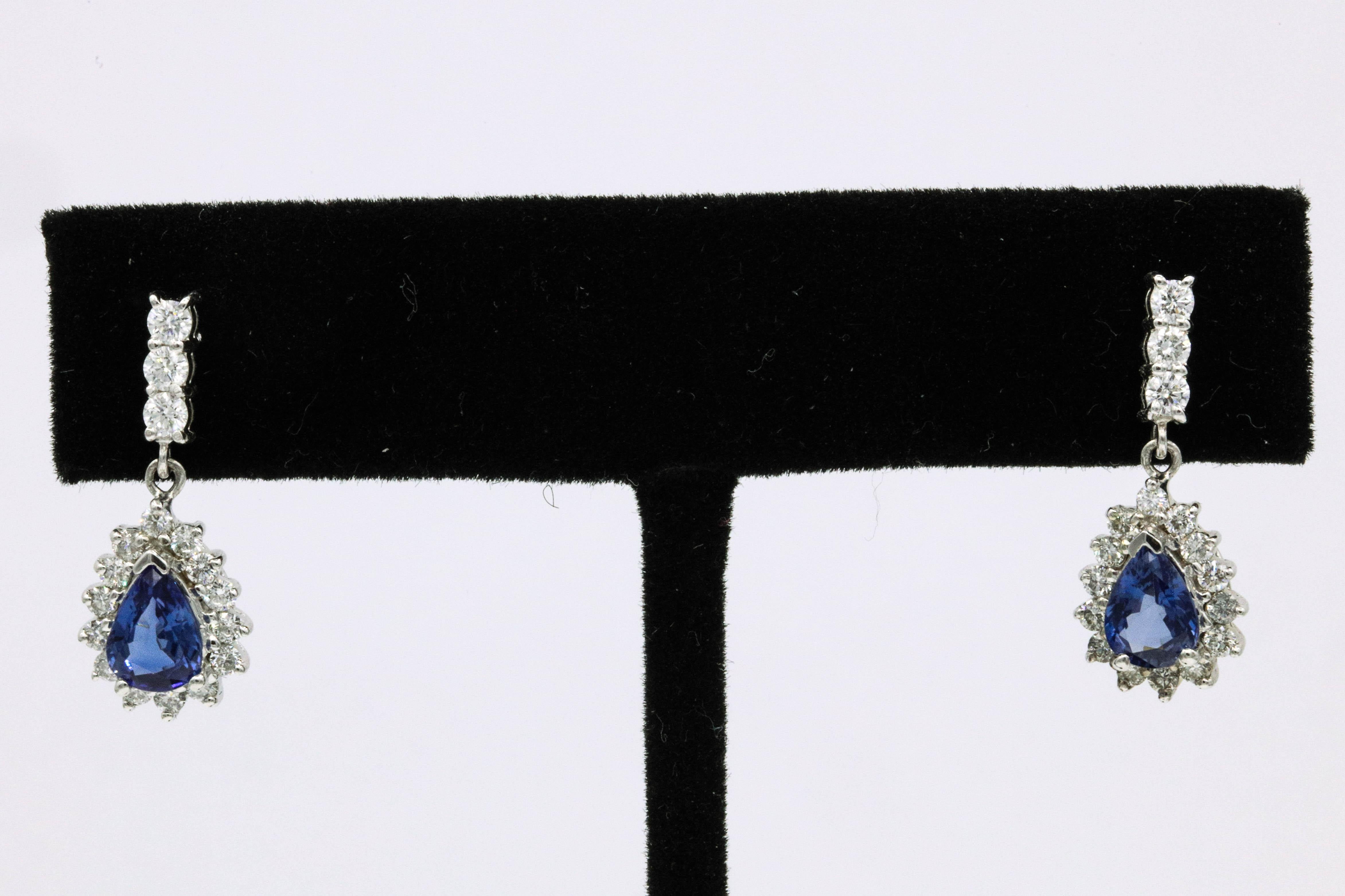 18K White gold drop earrings featuring two pear shape Nigerian Sapphires, 1.56 carats, flanked with round brilliants weighing 0.77 carats.