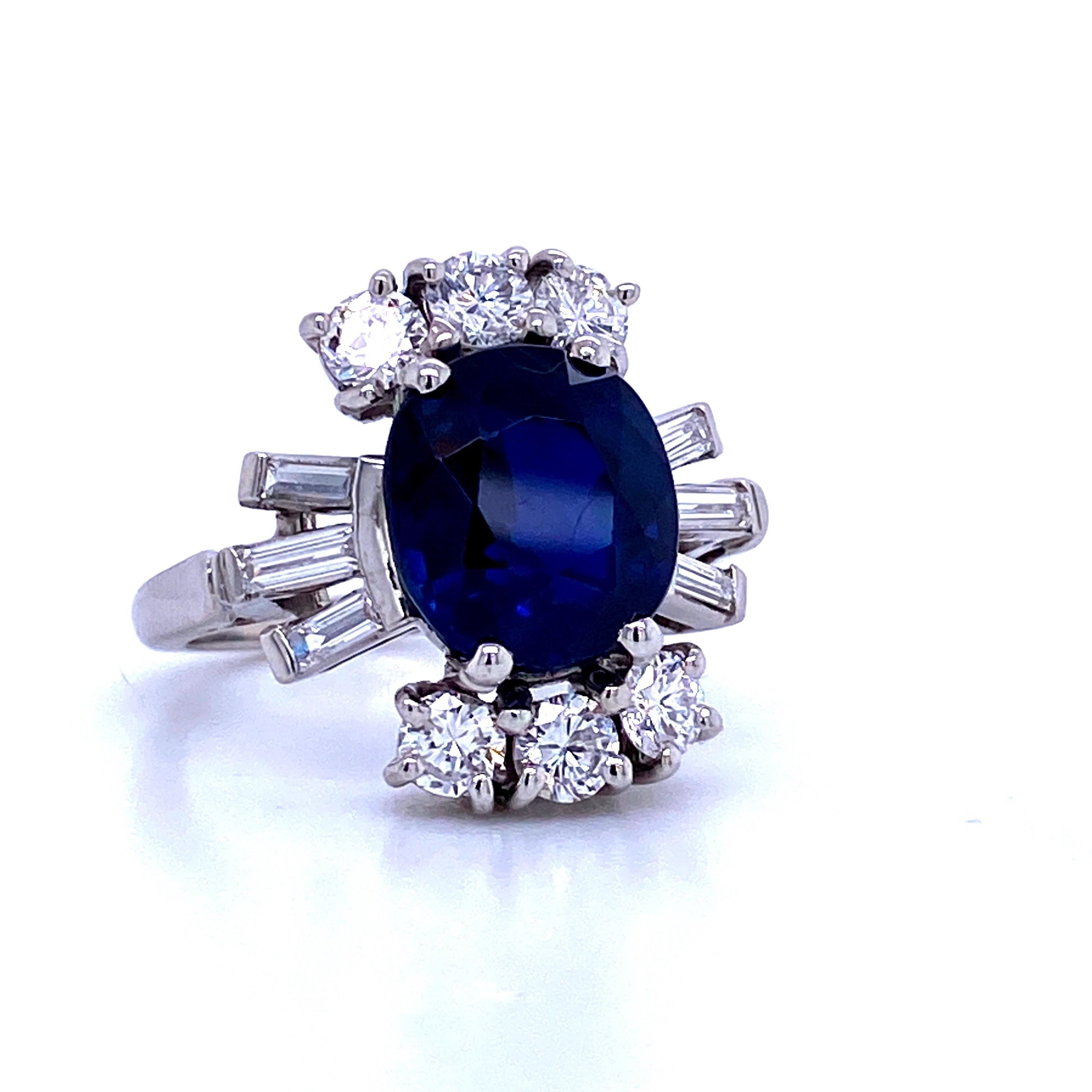 Platinum cocktail ring featuring one oval shape Sapphire weighing 5.12 carats flanked with round brilliants and baguette diamonds weighing 1.40 carats. 
Color G
Clarity SI