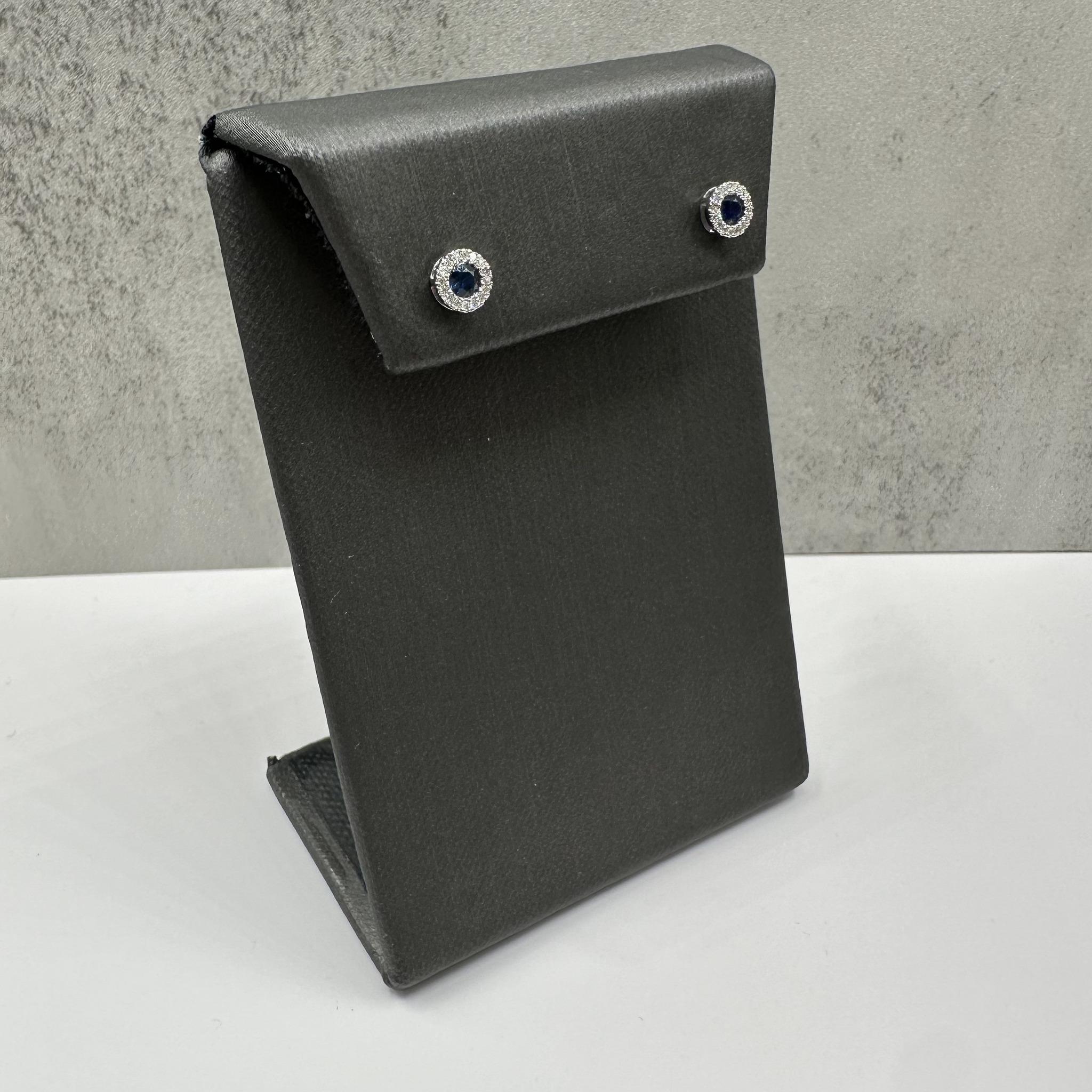 Diese klassischen Saphir- und Diamantohrringe aus 14-karätigem Weißgold bestehen aus zwei 3 mm großen, runden blauen Saphiren, die von 0,10 ct natürlichen Diamanten im Einzelschliff (GH I1) betont werden. Das elegante Design ist perfekt für den