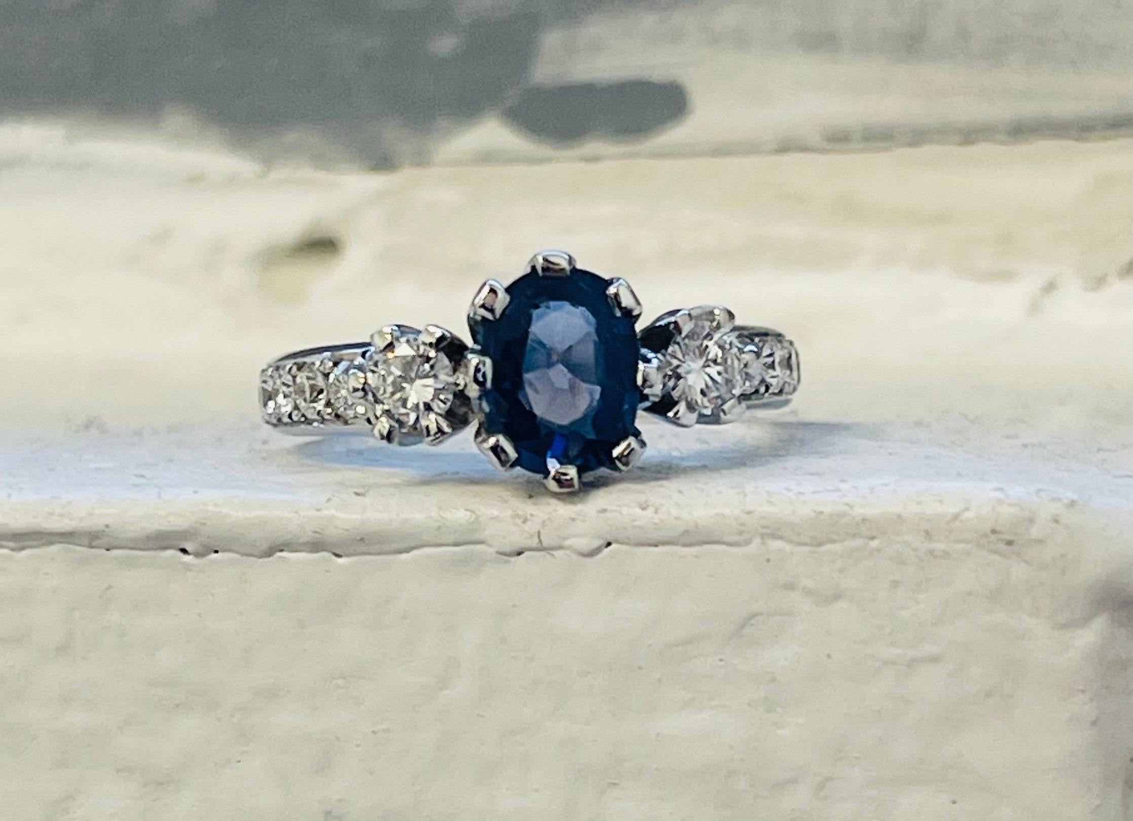 Élégante bague de fiançailles en saphir et diamant composée d'un saphir central de 1ct et de diamants latéraux totalisant 0,80 carats en or blanc 18KT. La bague est tellement classique, faite avec un design à trois pierres à l'esprit. Les diamants
