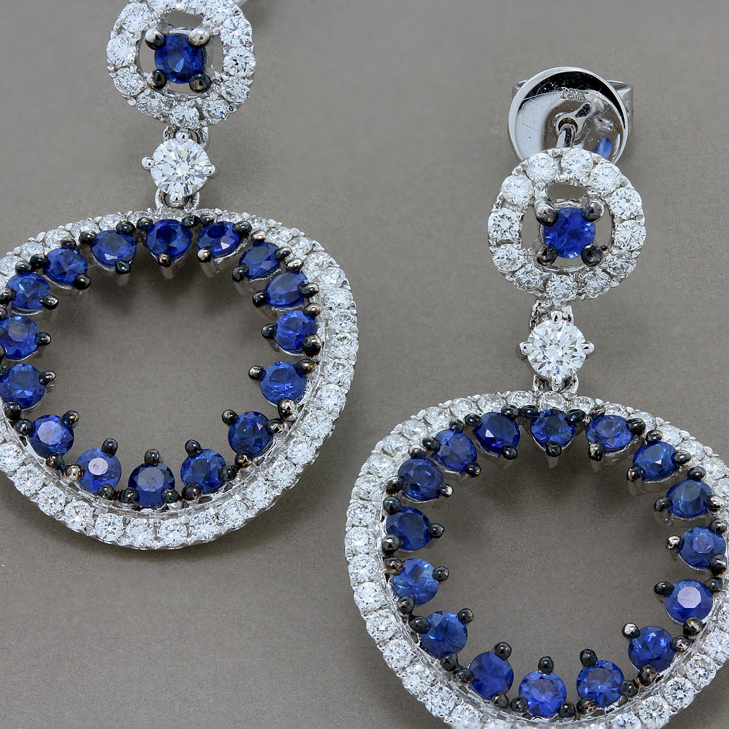 1.94 carats of fine blue round cut sapphires set within a 1.39 carat halo of round cut white diamonds. A unique pair set in 18K white gold with accents of black rhodium.

Earring Length: 1.75 inches
Earring Width: 0.75 inch

