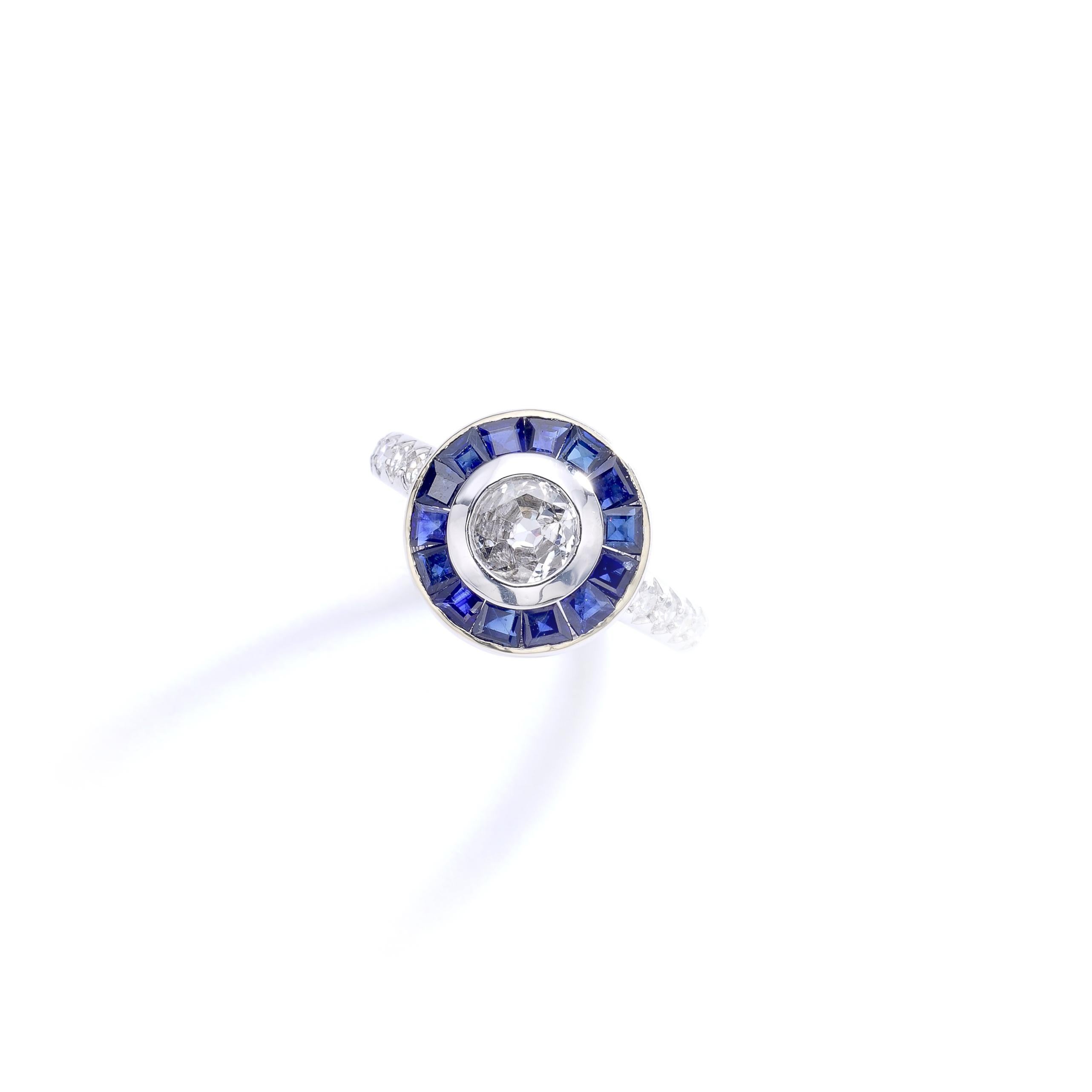 Bague contemporaine en or blanc 18k 750 centrée d'un diamant rond (environ 0,50 carat) entouré d'un saphir bleu calibré et effilé par un diamant.
Marques italiennes.

Taille de la bague : 6 1/4.