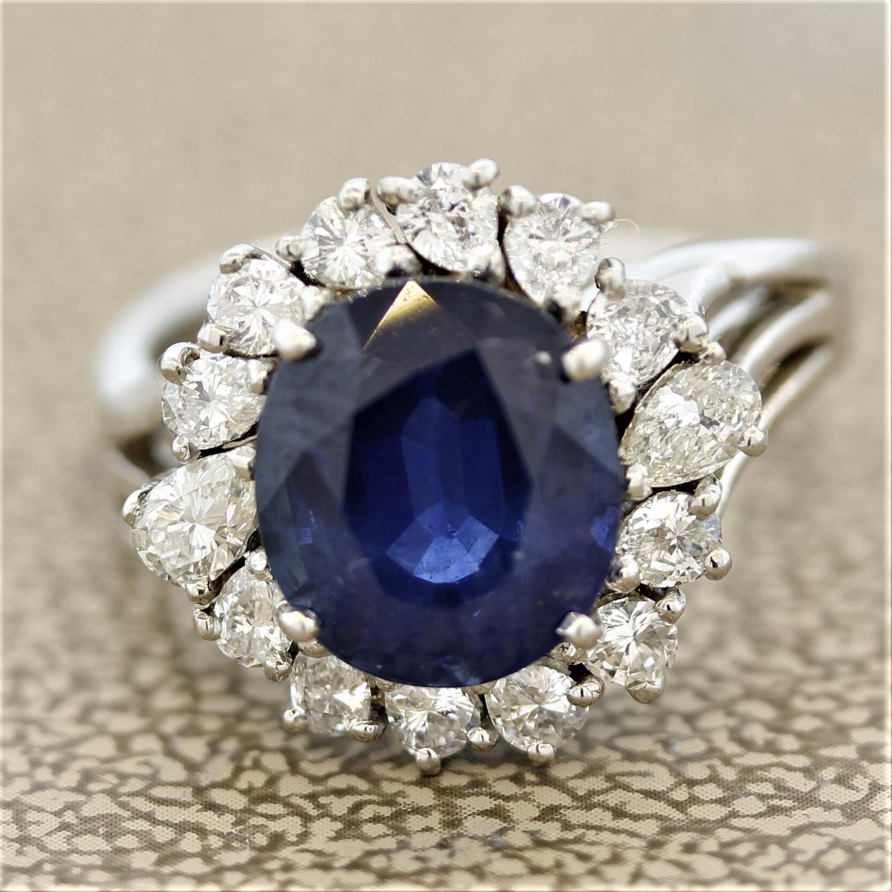 A classic sapphire ring! It features a luscious 3.49 carat oval shaped blue sapphire. It has a sweet blue color and is free of any eye-visible inclusions. It is haloed by 0.75 carats of round brilliant and pear shaped diamonds. Hand-fabricated in