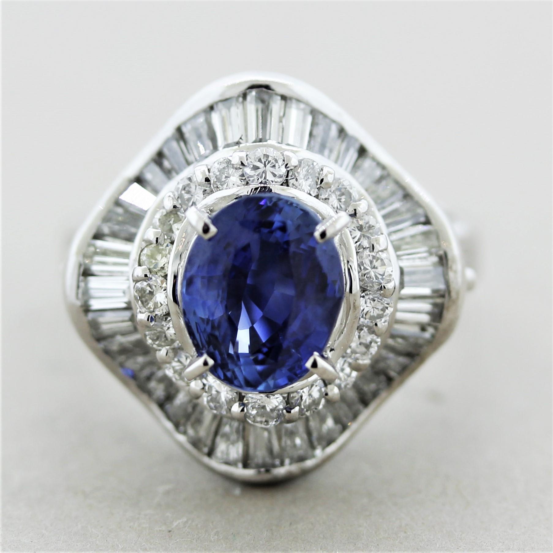 A luscious 2.06 carat oval-shaped sapphire takes center stage. It has a bright and rich royal blue color and is free from any eye-visible inclusions. It is accented by a double halo of round brilliant and baguette-cut diamond set around the