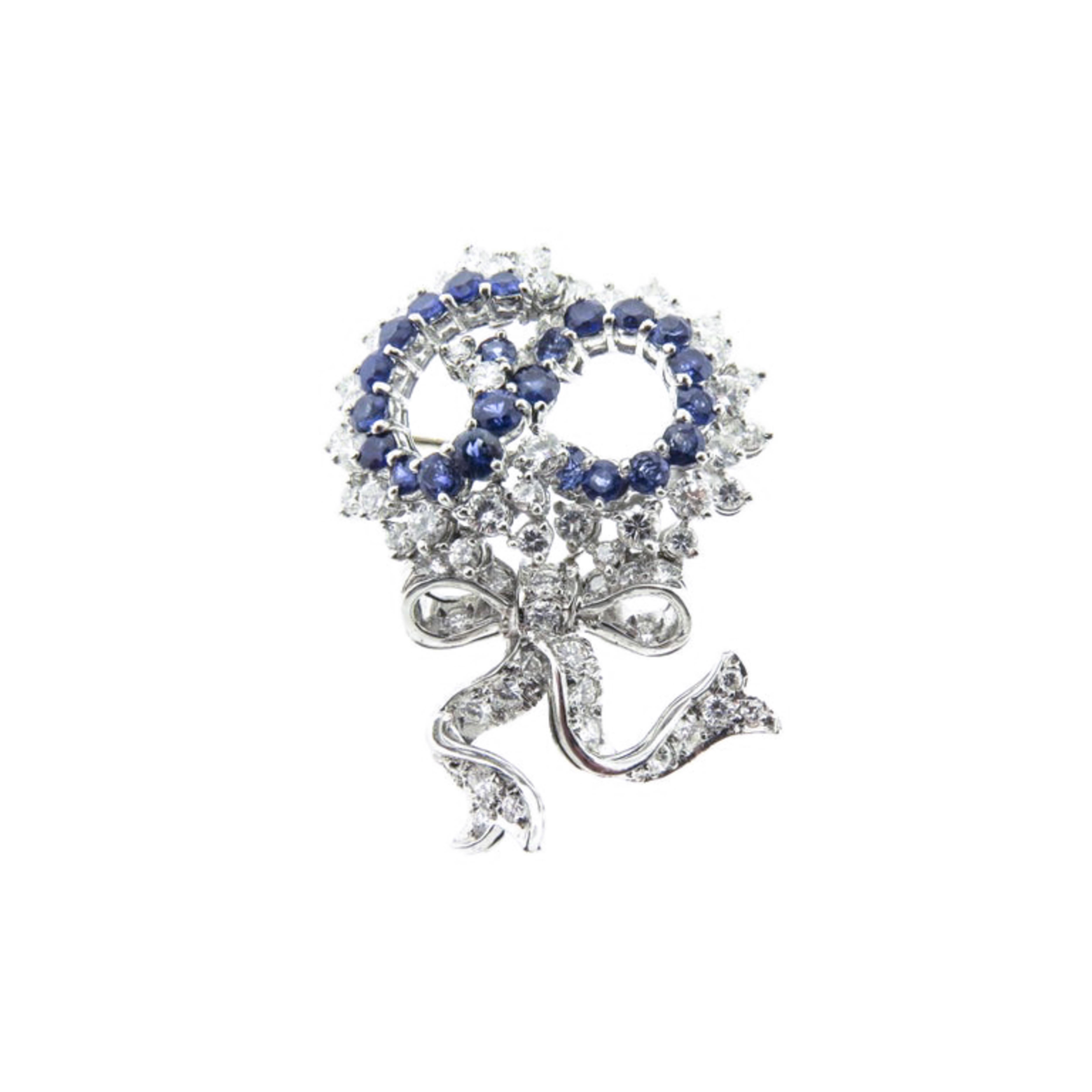 This whimsical 'ribbon swirl' platinum brooch is set with a multitude of white diamonds and blue sapphires has a very timeless feel. 
Crafted in Platinum with an amazing arrangement of approximately 64 round Diamonds, totaling 4.72 carats and 23