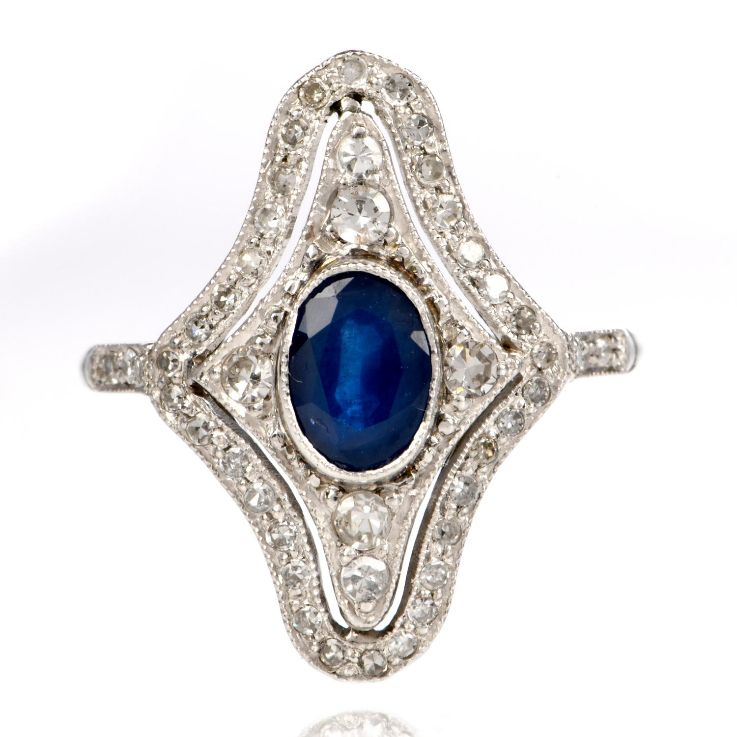 This Stylish Estate blue sapphire and diamond ring is crafted in platinum, weighing 3.7 grams and measuring 21 mm wide. Designed as a stylized lozenge plaque, this classically and timelessly elegant ring is centered with a 0.90 carat oval-cut blue