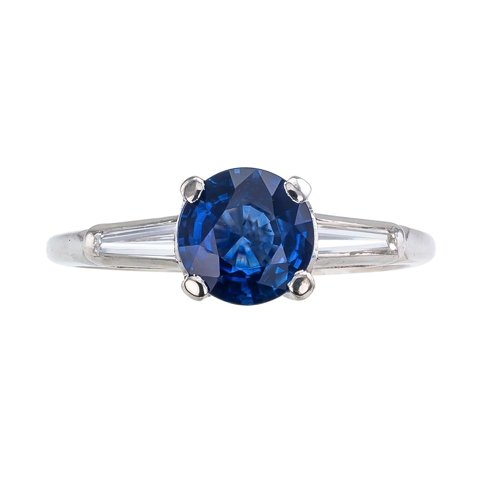 Sapphire and diamond platinum engagement ring circa 1950.

DETAILS:
GEMSTONES: one round, faceted blue sapphire weighing approximately 1.11 carats.

DIAMONDS: two tapered baguettes totaling approximately 0.20 carat, approximately H color and VS