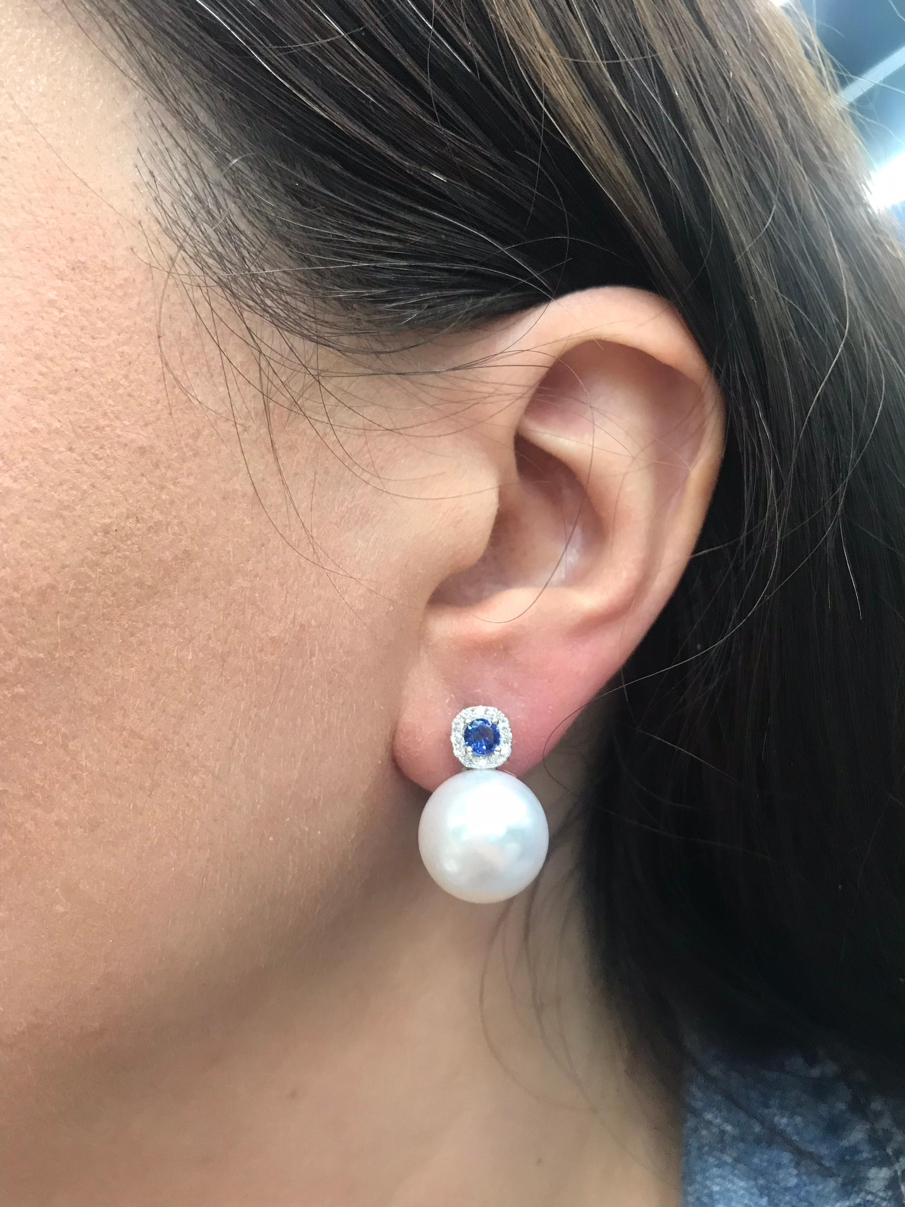 18K White gold drop earrings featuring two sapphires weighing 0.60 carats flanked with round brilliants, 0.24 carats, and two South Sea Pearls measuring 14-15mm. 