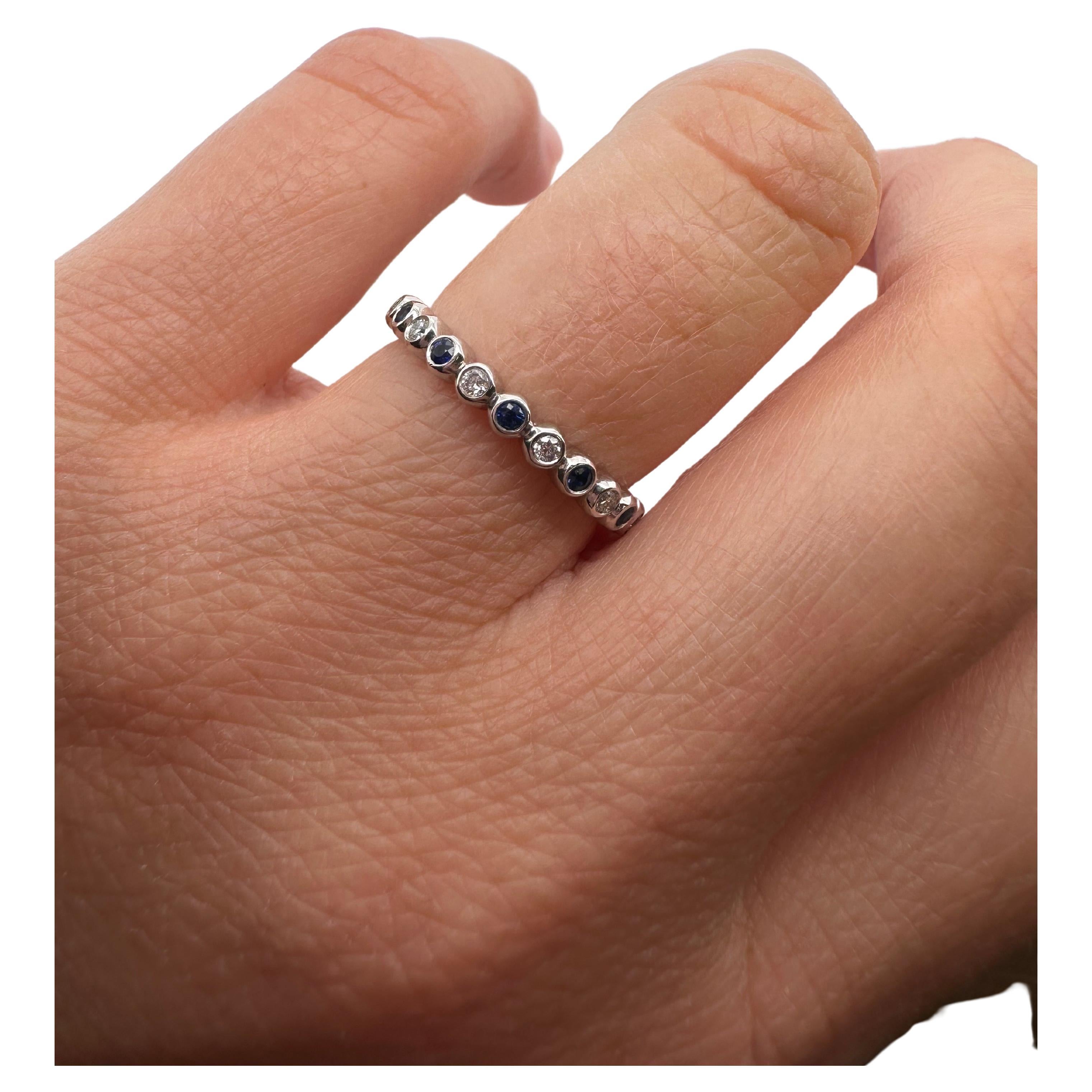 Blue sapphire and diamond ring in 14KT white gold, eternity ring bezel set.

Metal Type: 14KT
Gram Weight:4 grams 

Natural Sapphire(s):
Color: Dark Blue
Cut:Round
Carat: 0.30ct
Clarity: Moderately Included

Natural Diamond(s): 
Color: F-G
Cut:Round