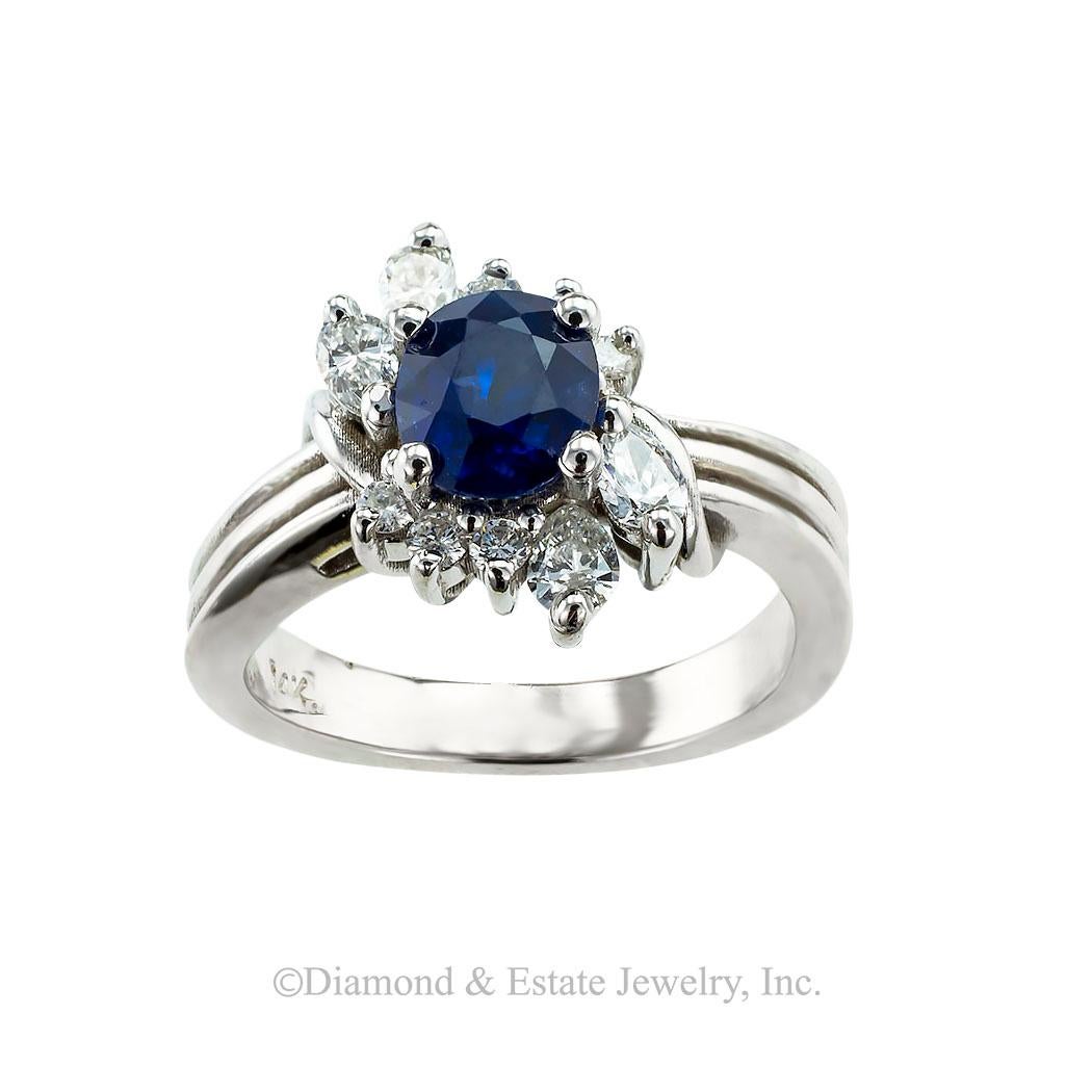 Sapphire diamond and white gold cluster ring circa 2000. *

SPECIFICATIONS:

CENTER GEM:  one oval-shaped, faceted, blue sapphire weighing approximately 1.00 carat.

DIAMONDS:  ten marquise-shaped, pear-shaped, and round brilliant-cut diamonds