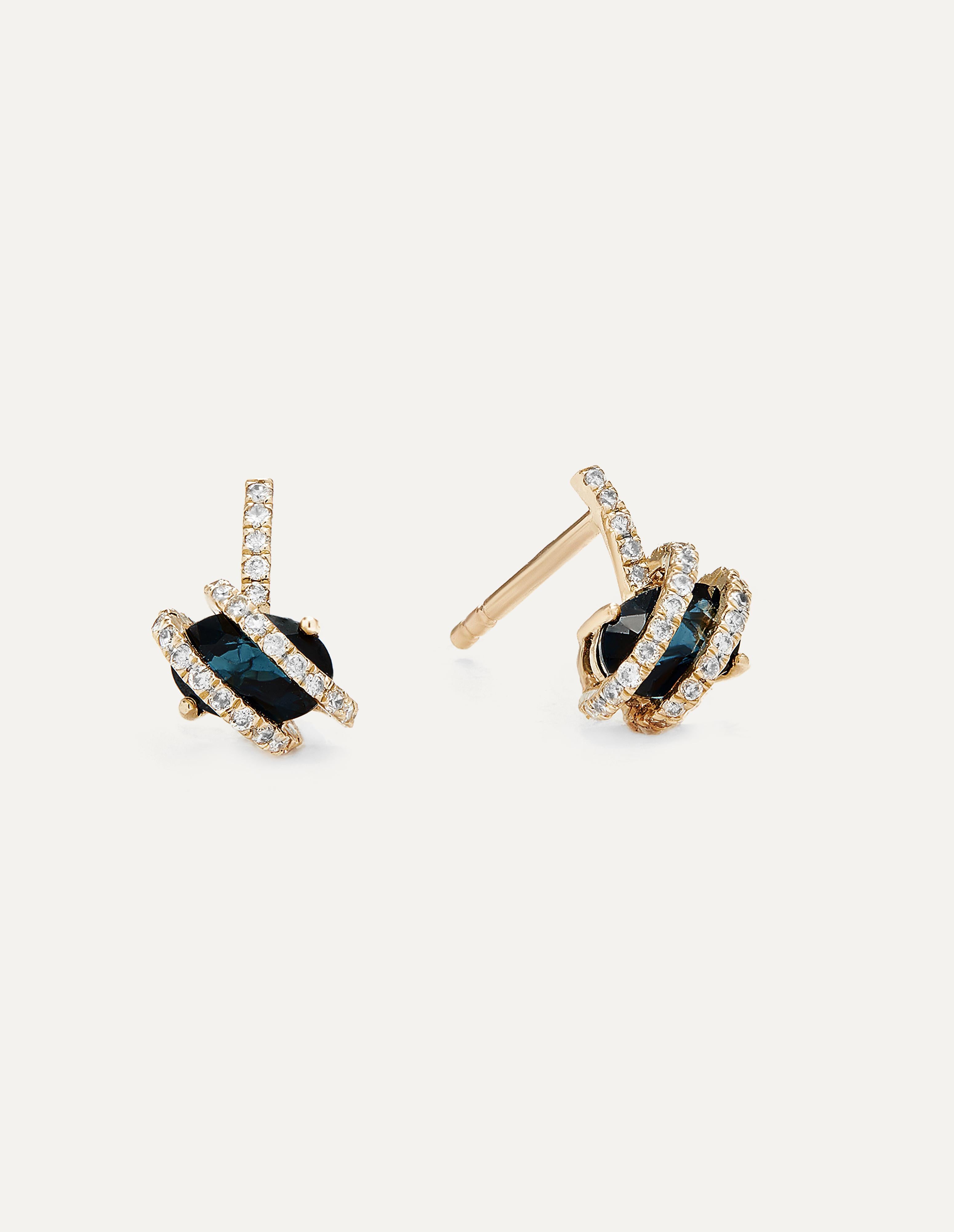 The Oval Sapphire Diamond Wrap Studs in 14k yellow gold are a stunning embodiment of nature's beauty and luxury. These stud earrings feature a captivating design, where lustrous oval sapphires are cradled by a wrap of brilliant white diamonds,