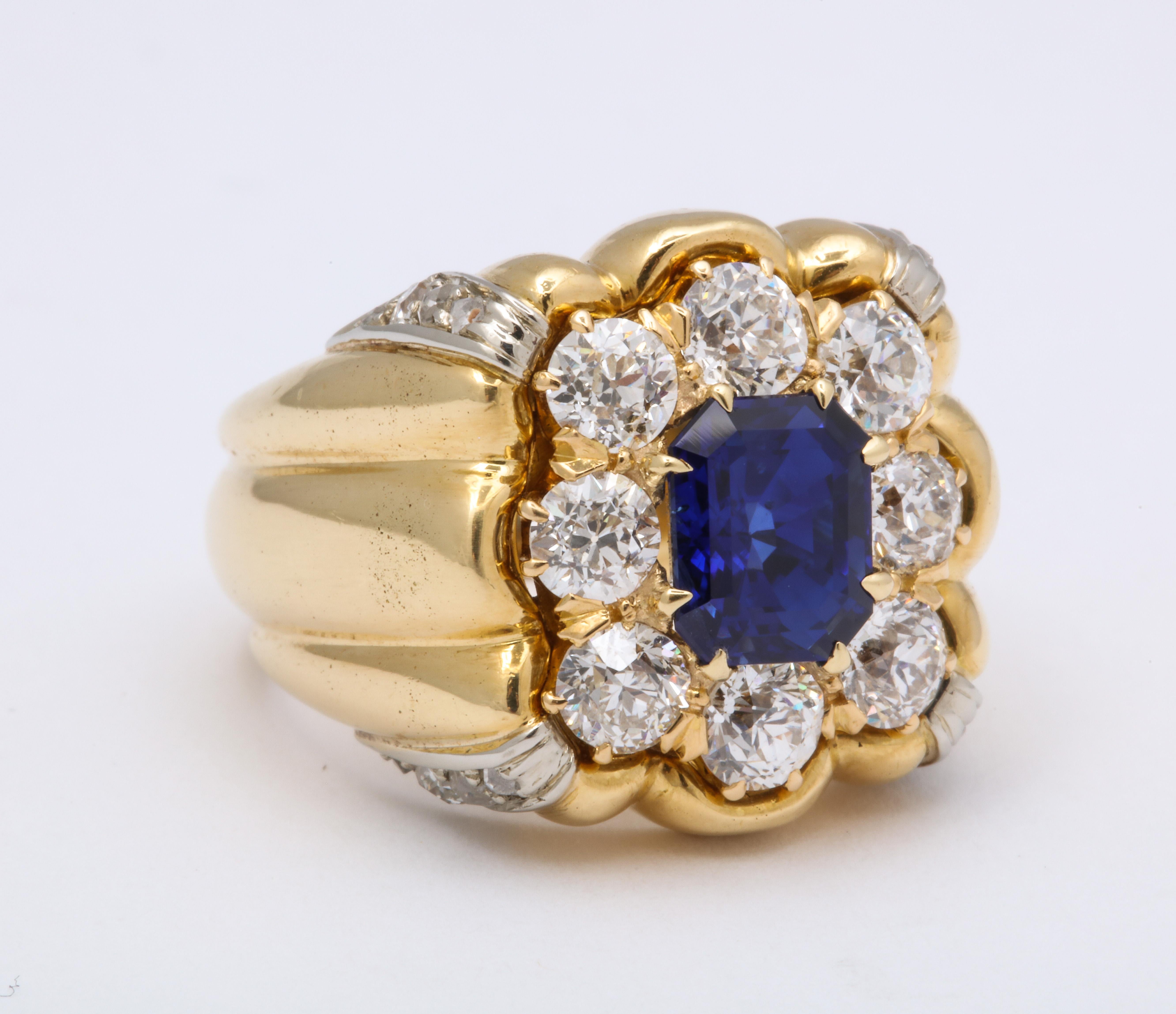 Diamond sapphire yellow gold unisex ring.  The emerald cut sapphire is approximately 2.40 carats. There are 8 full and 12 single cut diamonds totaling 2.15 carats.   3/4 inch w x 3/4 inch high and 3/8 inch deep.

Materials:
18K Yellow Gold, 24