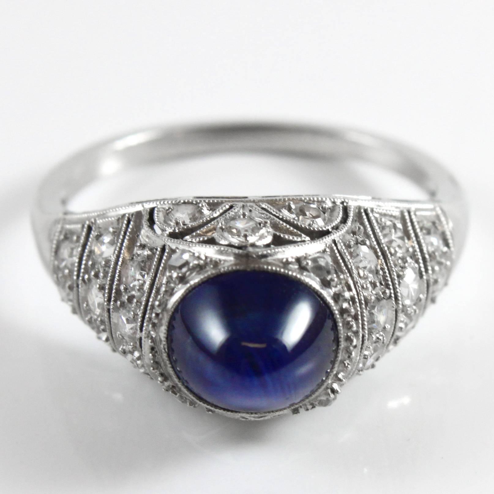 Sapphire cabochon and diamond ring in white gold. The sapphire weighs circa 3 carats and has a beautiful deep blue colour. It accentuates beautifully like a dome and surrounded by single cut diamonds.