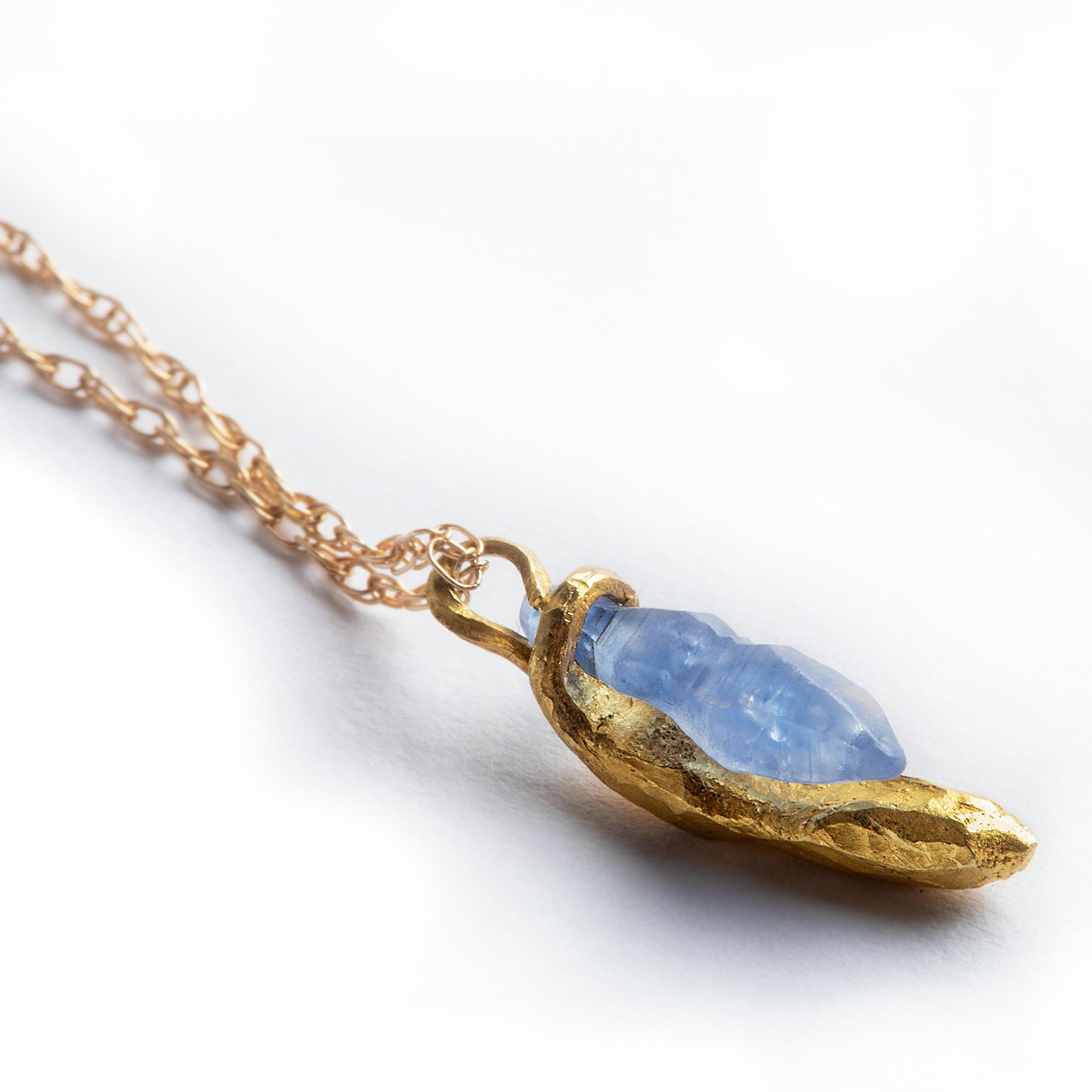 This delicate pendant necklace connects a beautifully formed 1.05ct rough sapphire crystal and a 22k yellow gold miniature sculpture forged to embrace and wrap around the stone.

The embrace hangs lightly from an airy 16-inch 18k gold rope
