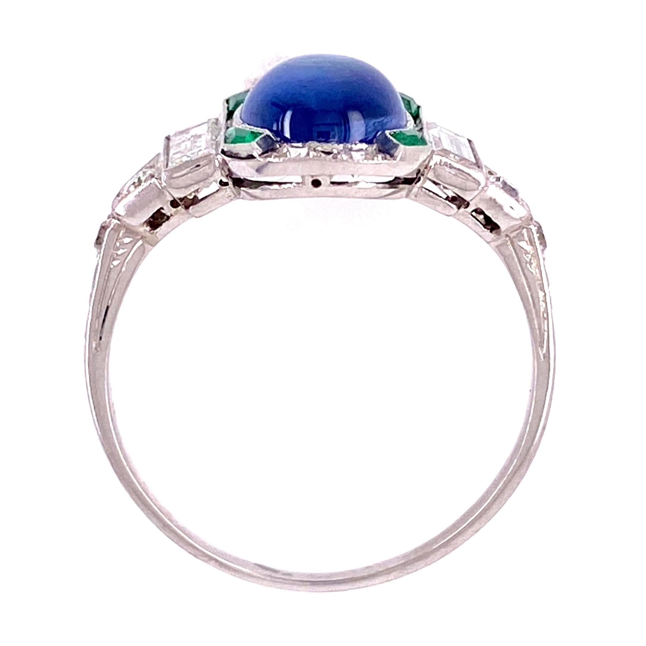 Beautiful and finely detailed Sapphire, Emerald and Diamond Cocktail Ring, center securely set with a cabochon Blue Sapphire weighing approx. 1.45 Carat accented by 4 custom cut Emeralds, weighing approx. 0.09 carats and baguette and round Diamonds