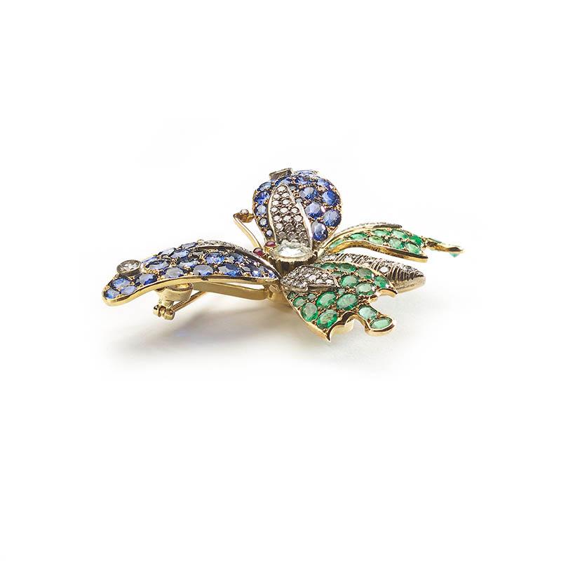 A sapphire, emerald and diamond butterfly brooch, with a rose-cut diamond set thorax, weighing an estimated 0.80ct, round brilliant-cut diamond set abdomen and cabochon-cut ruby eyes and a diamond set head and antenna, the fore-wing is set with