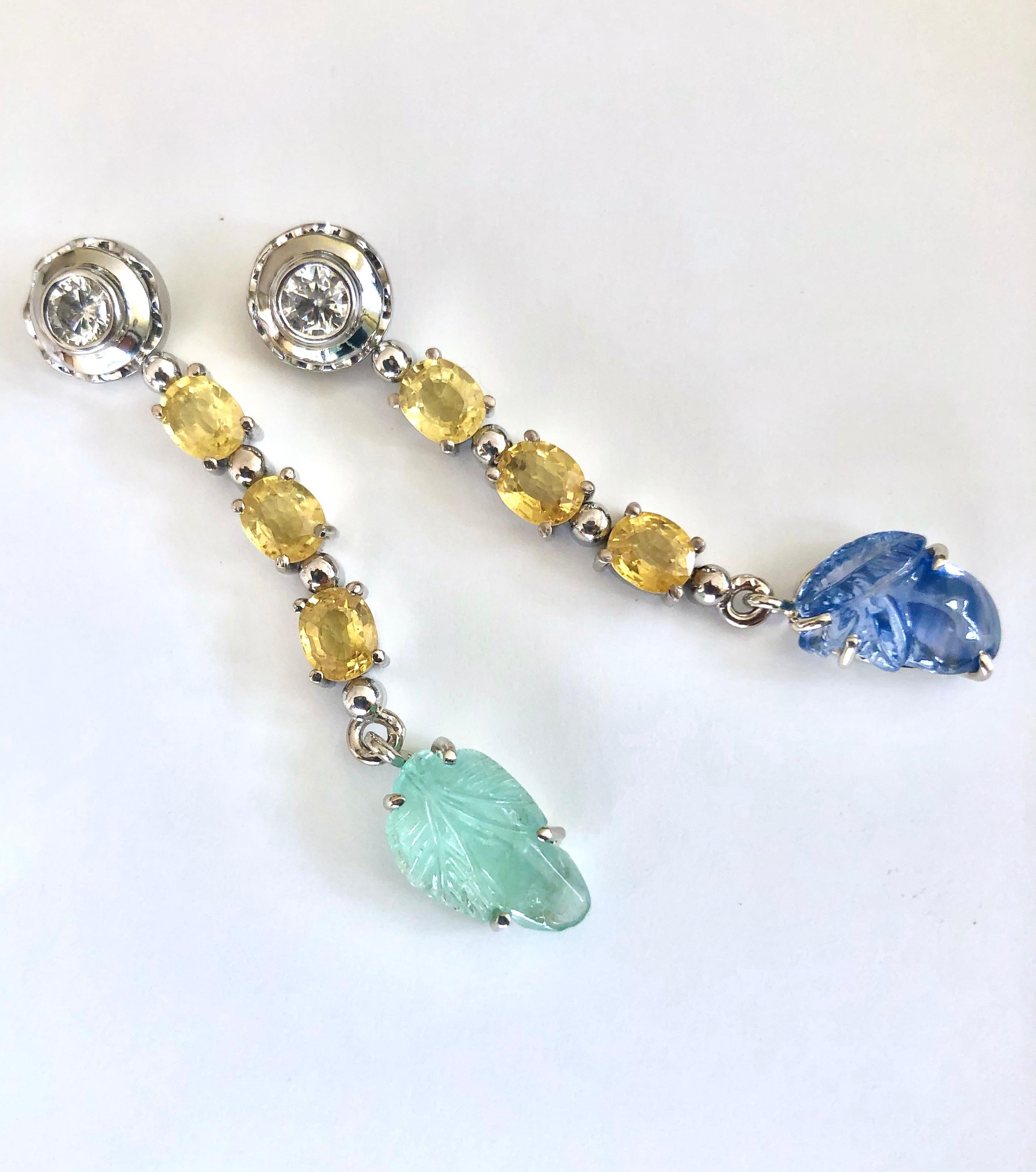 A stunning pair with beautiful quality sapphires, and diamond emerald drop dangle earrings! 
The earrings have a total weight of 9.10 carats of carved sapphire and emerald leaf motifs that hang beautifully from three oval yellow sapphires. The total