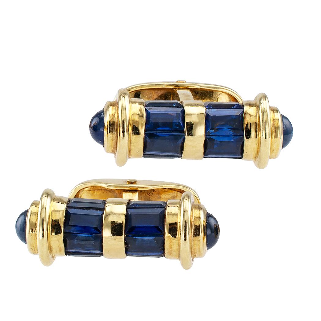 Sapphire and gold cufflinks circa 1990. The matching baton designs feature twin courses of channel-set, square baguette sapphires, capped at the ends with round cabochon sapphires, mounted in 18-karat yellow gold, the sapphires together totaling