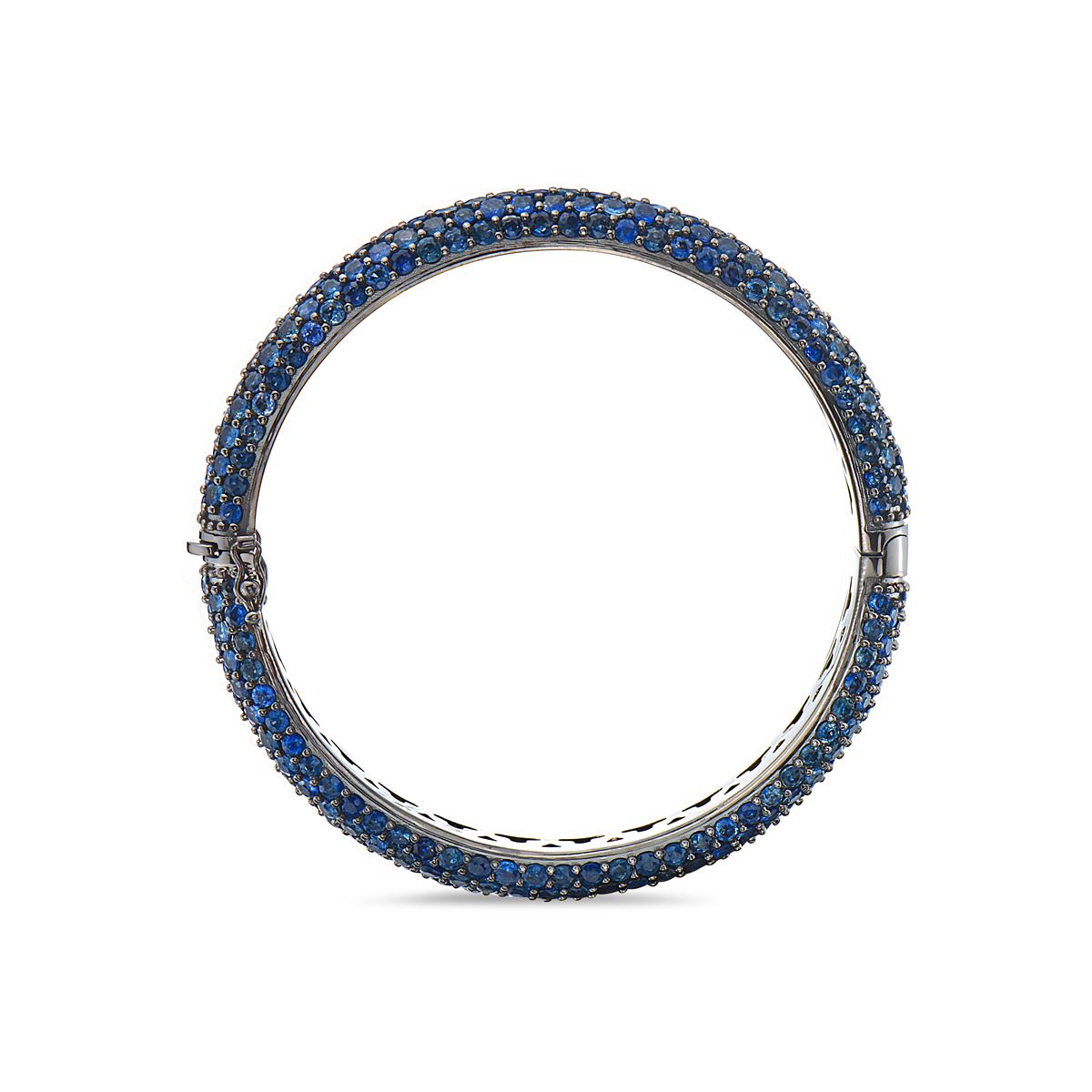 This bangle features 336 round cut blue sapphires weighing 27.46 carats set in 14K gold that is coated in black rhodium. Measuring 2 3/8 inches in diameter and weighs 50 grams total weight. Features a double clasp closure. Made in USA.