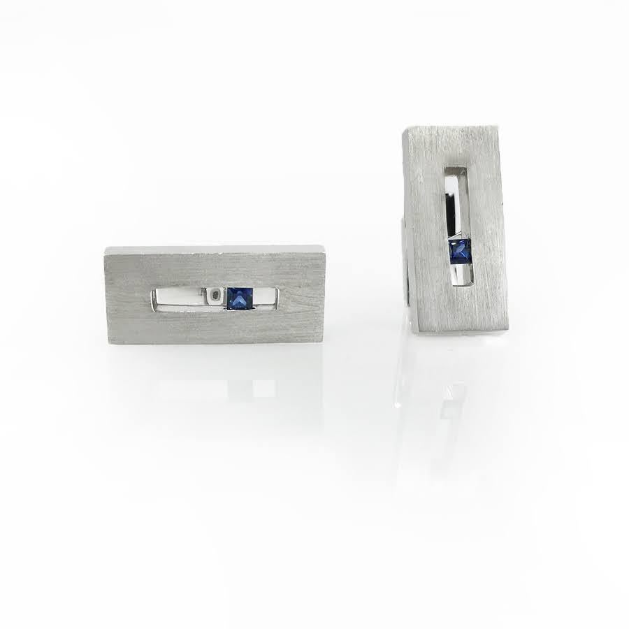 These Sapphire in White Gold Suspended Rectangle Cufflinks are a masculine touch in our Suspension Collection. Shown in 18k white gold with approximately .25 pts total weight in blue sapphires with a matte finish. Whether worn with a dinner jacket