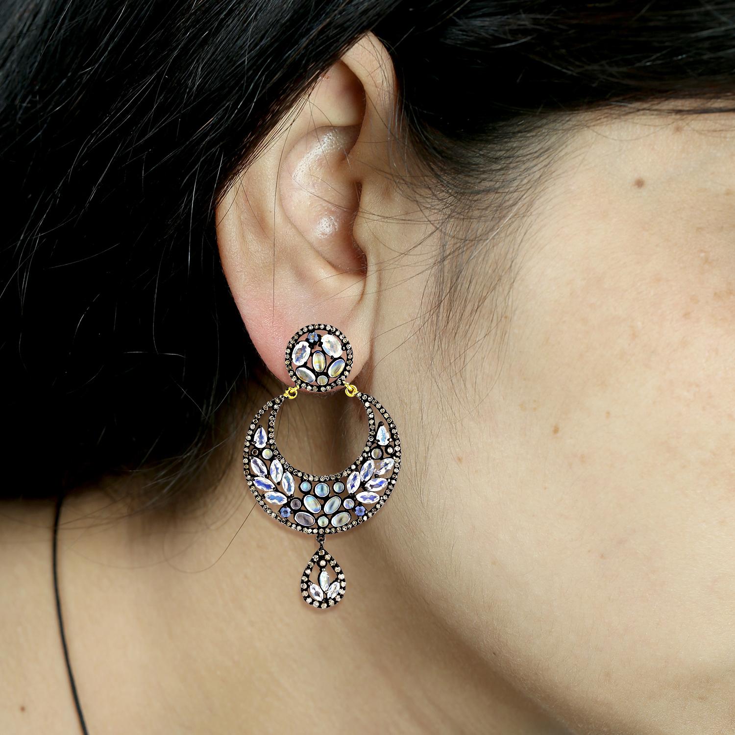 Ces étonnantes boucles d'oreilles en forme de demi-lune présentent un magnifique mélange de saphirs et de pierres de lune, rehaussé de diamants pavés étincelants. La combinaison des riches saphirs bleus et des pierres de lune blanches éthérées crée