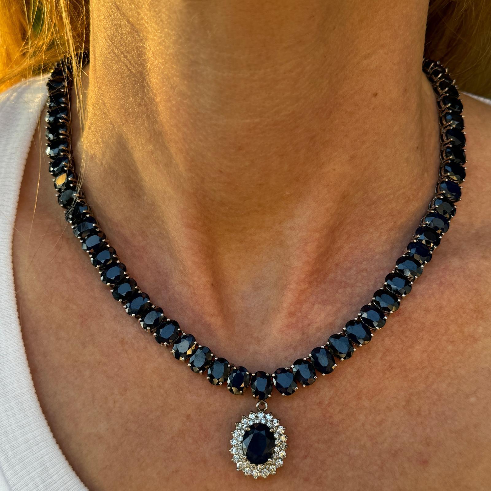 Impressive sapphire gemstone necklace crafted in 14 karat white gold and detachable diamond and sapphire drop pendant. The necklace and pendant feature 73 natural blue sapphires weighing approximately 105.5 carat total weight. The pendant features