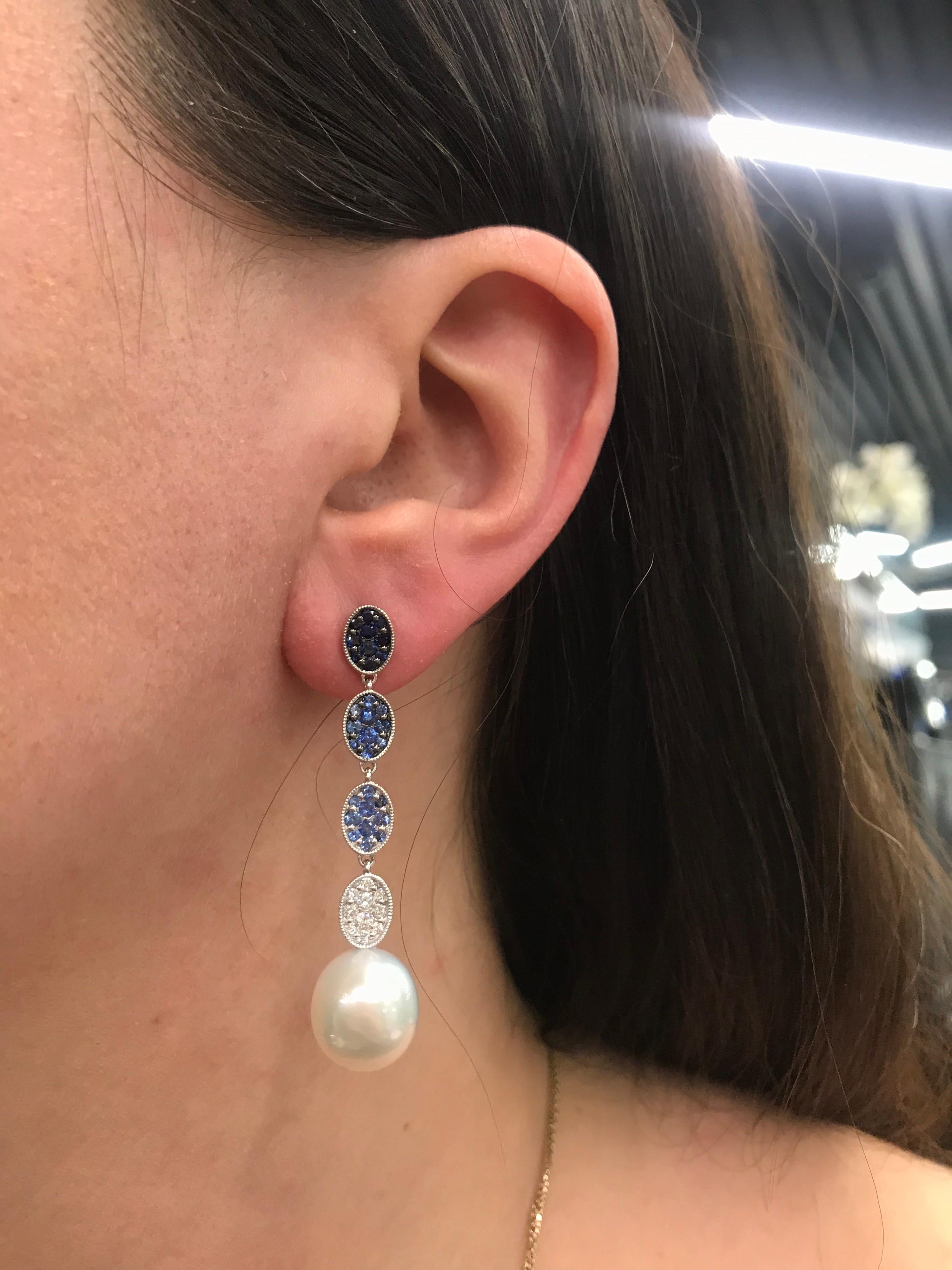 18K White gold drop earrings featuring ombree light blue to dark sapphires weighing 1.38 carats, 20 round brilliants weighing 0.34 carats and two South Sea Pearls measuring 11-12mm