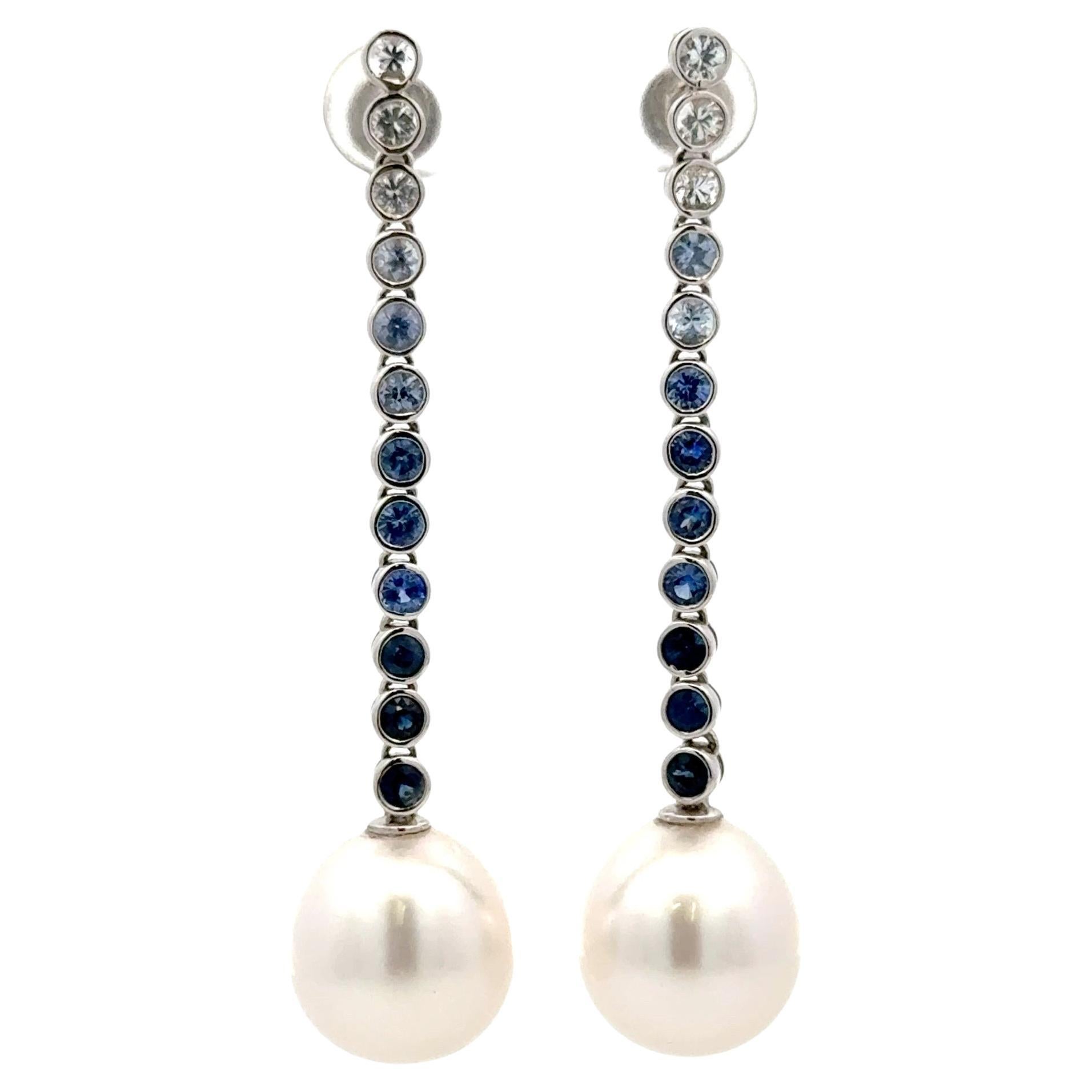 Boucles d'oreilles pendantes en or blanc 18 carats présentant un motif ombré de saphirs blancs et bleus et deux perles blanches des mers du Sud mesurant 13-14 mm.
6 saphirs blancs pesant 0,58 carats et 18 saphirs bleus pesant 1,66 carats.