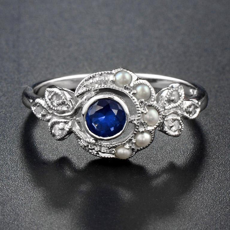 A Victorian Classic 9K White Gold Ring curves around the top of the finger for comfortable everyday wear. The Center is Sapphire 0.32 ct. and surrounding with Pearl 5 pcs. 0.3 ct. and Rose Cut Diamond 6 pcs. 0.05 ct. on leaf shoulder.
Currently size