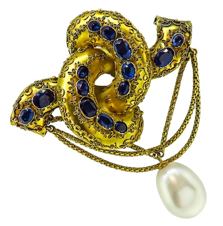 This elegant 14k yellow gold pin is set with lovely oval cut sapphires that weigh approximately 6.00ct. The sapphires are accentuated by a gorgeous baroque pearl.
The pin measures 70mm by 61mm and weighs 20.9 grams.


Inventory #93971PSSS