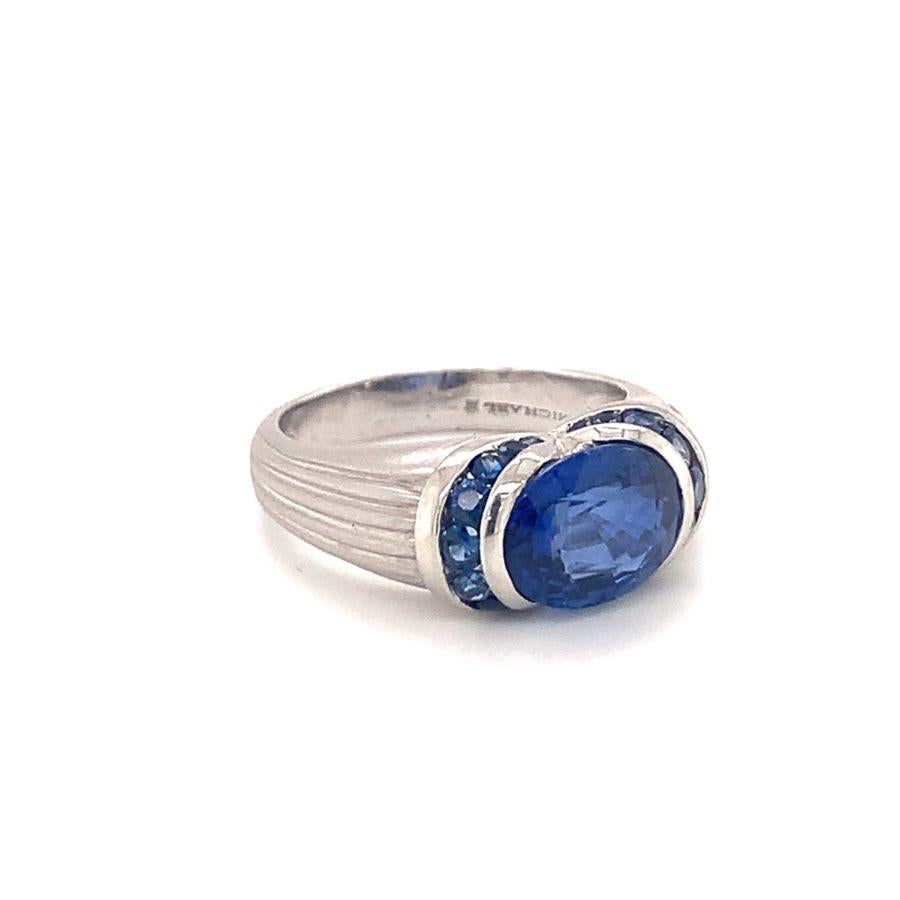 One sapphire platinum ring centering one oval cut, bezel and tension set sapphire weighing 3.71 ct. (exact weight) surrounded by 18 round cut sapphires totaling approximately 1 ct. With contemporary ribbed satin finish mount.

Powerful, vibrant,
